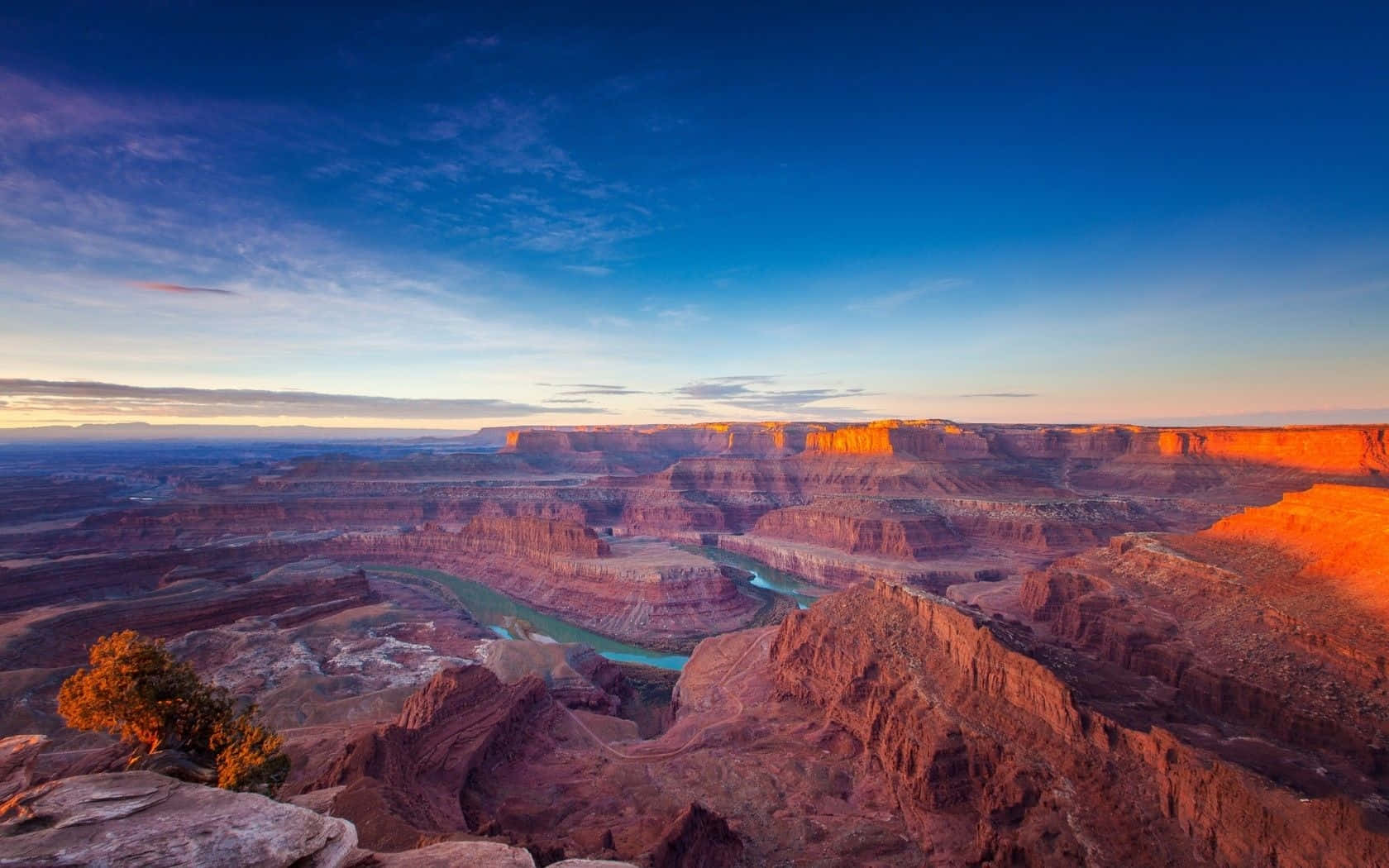 Arizona 桌布 壁紙 — 廣闊峽谷上令人驚嘆的日落，一條蜿蜒的碧綠河流穿過紅色岩層。
