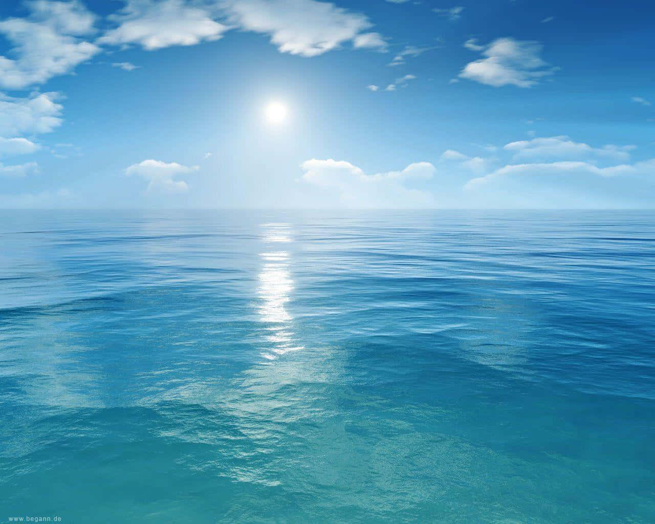 海洋藍 桌布 壁紙 — 廣闊平靜的海洋在明亮的陽光下延伸至地平線，蓬鬆的雲朵在碧綠的海水上投下柔和的光線。