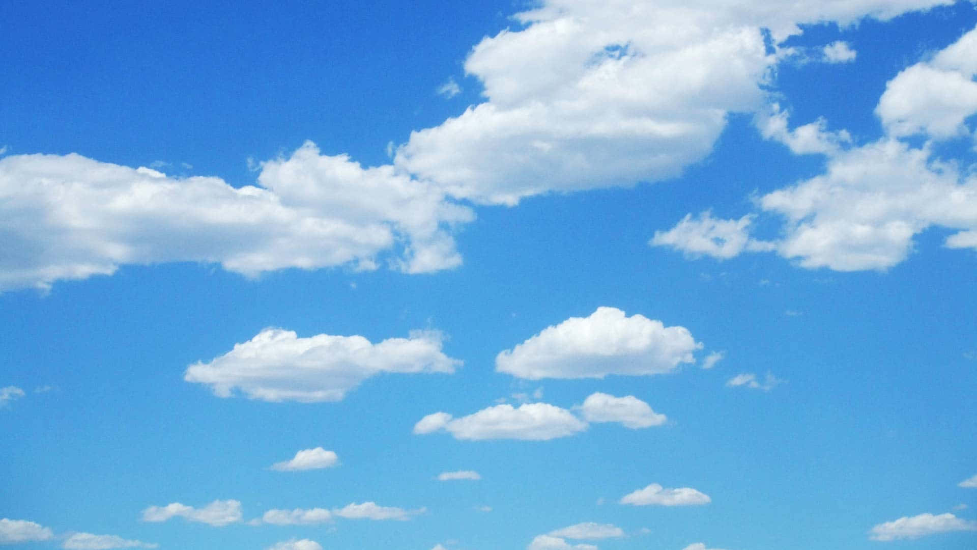 Blue Skies 桌布 壁紙 — 廣闊明亮的藍天，充滿蓬鬆的白雲，懶洋洋地飄過地平線。