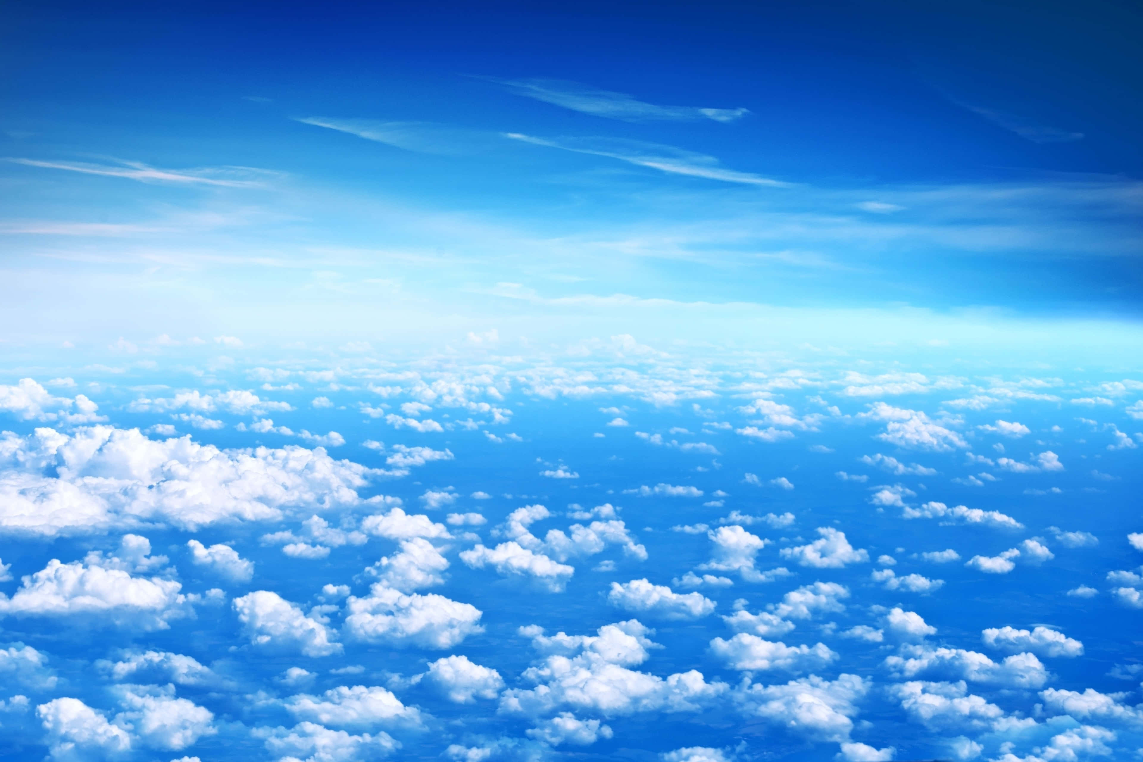 Clouds Aesthetics 桌布 壁紙 — 廣闊明亮的藍天，蓬鬆的白雲延伸至地平線。