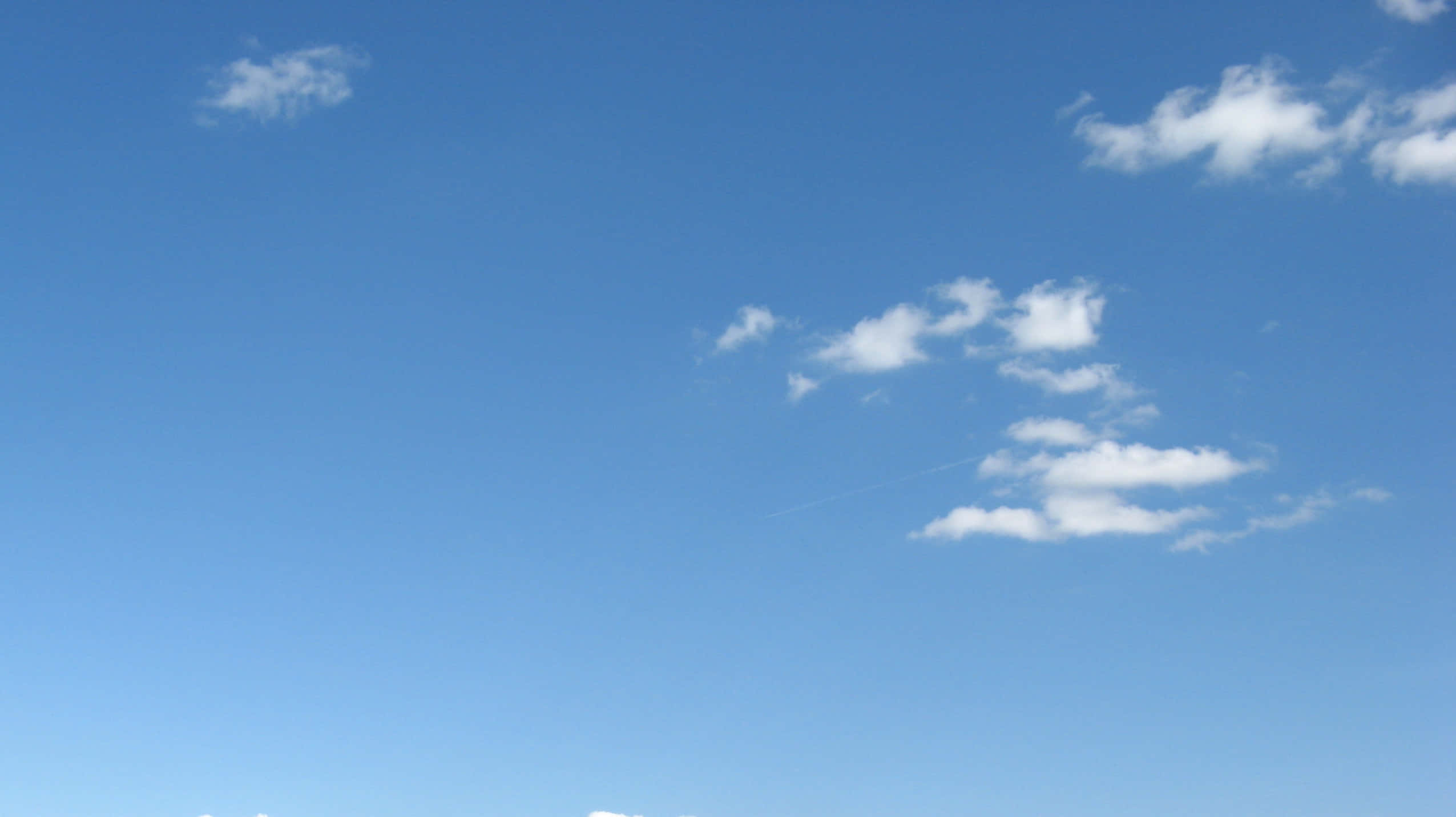 Blue Skies 桌布 壁紙 — 廣闊清澈的藍天，散落著蓬鬆的白雲和一條淡淡的飛機雲。