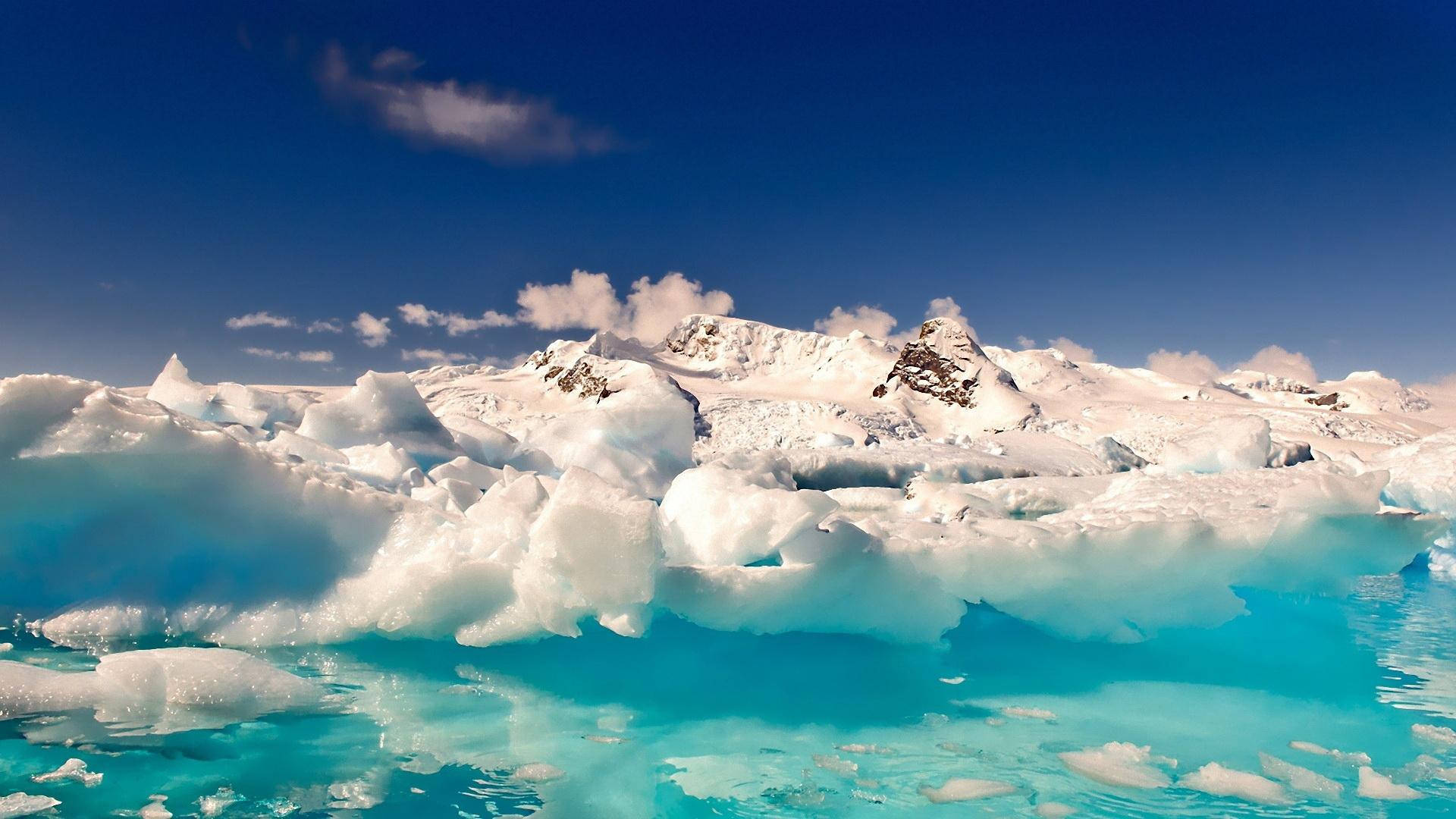Antarctica 桌布 壁紙 — 廣闊的冰河，帶有藍綠色融水，在清澈藍天和零星白雲下。