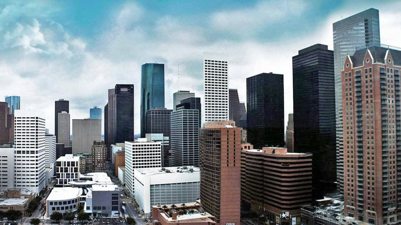 Houston 桌布 壁紙 — 廣闊的城市天際線，高聳的摩天大樓在部分多雲的藍天下，展現現代玻璃和混凝土建築風格。