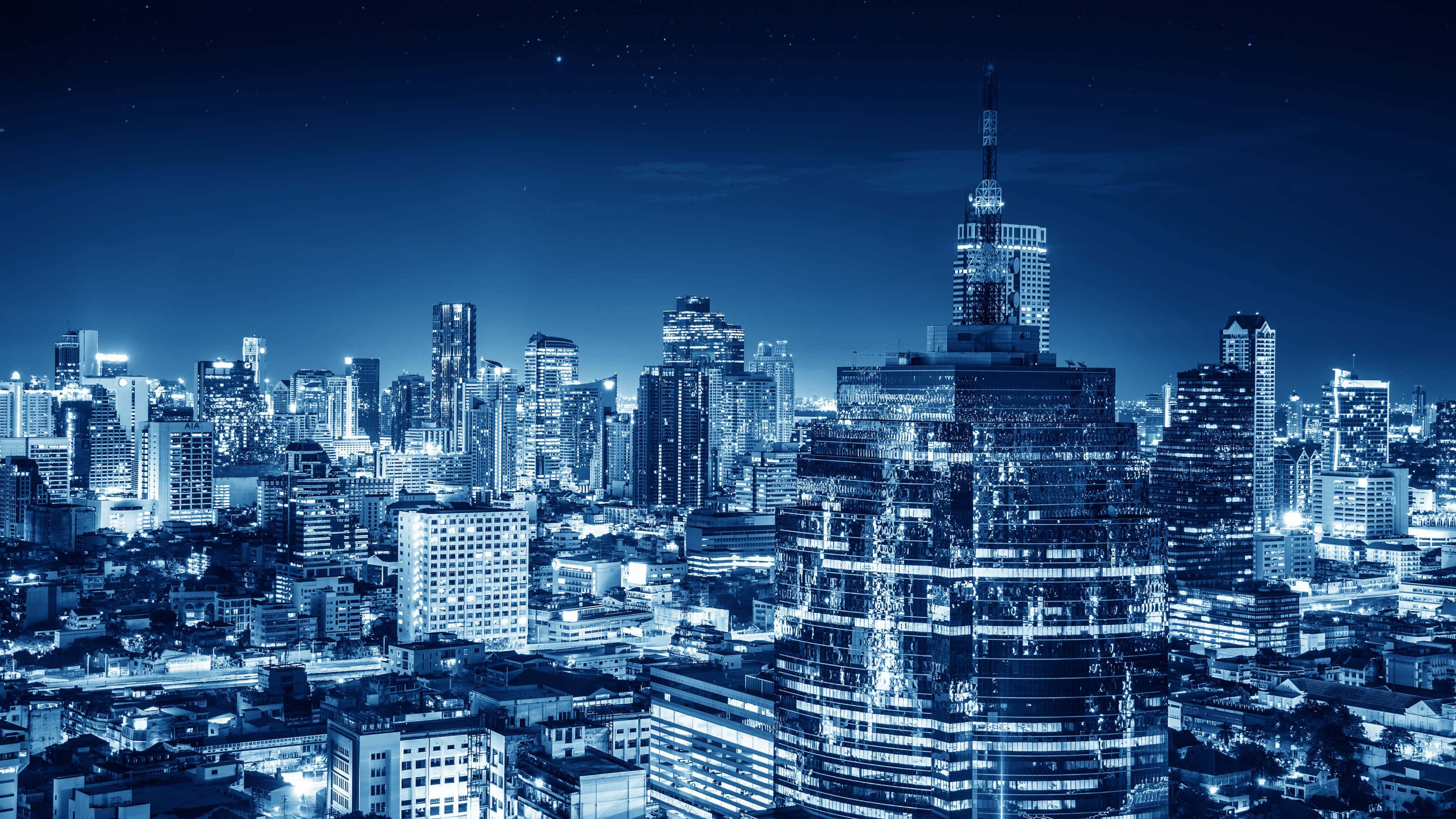 City Night 桌布 壁紙 — 廣闊的城市天際線夜景，沐浴在清涼的藍色調中，無數窗戶在星空下閃爍。