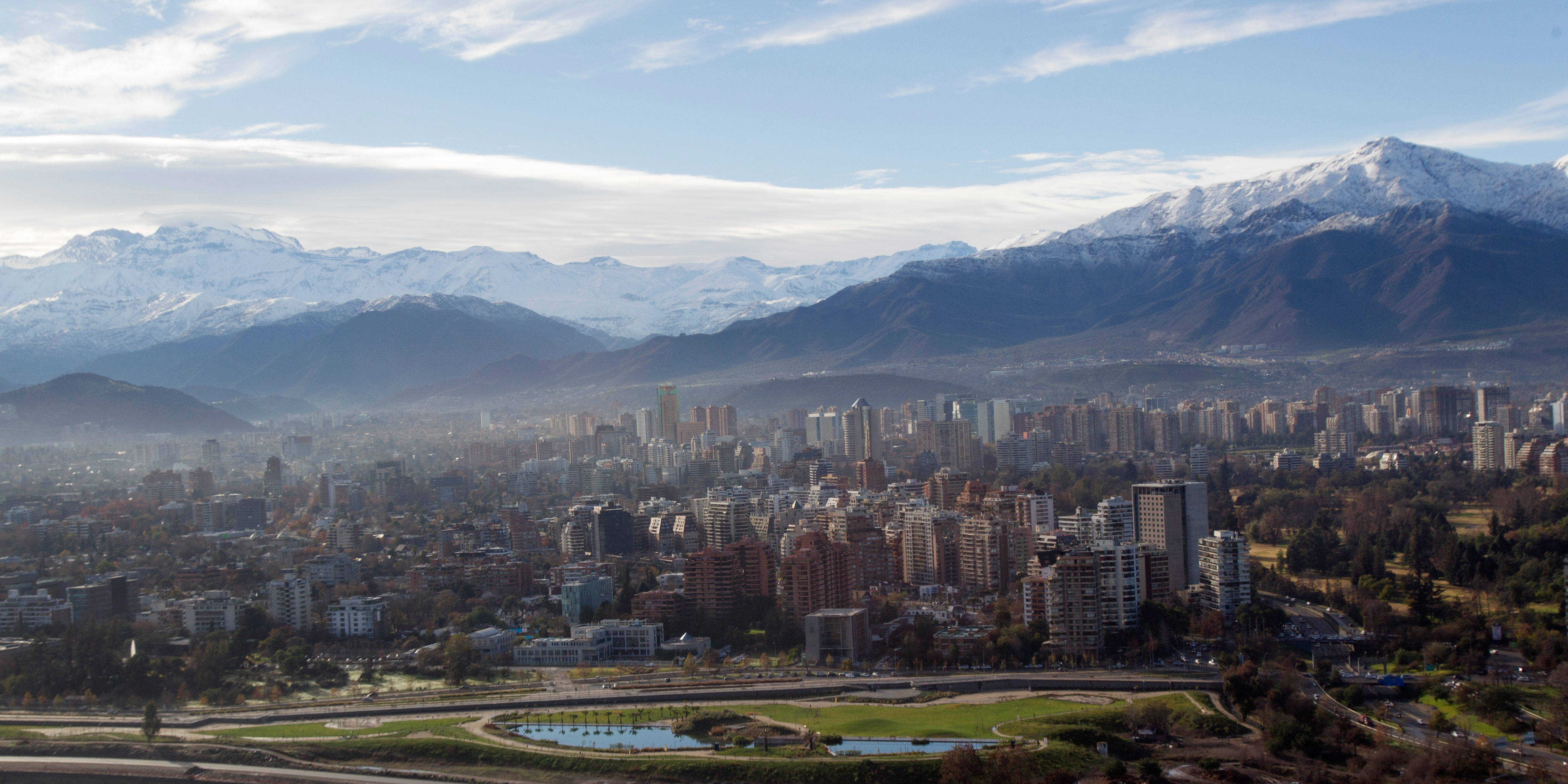 山景 桌布 壁紙 — 廣闊的城市景觀，坐落於積雪山腳下，藍天白雲。