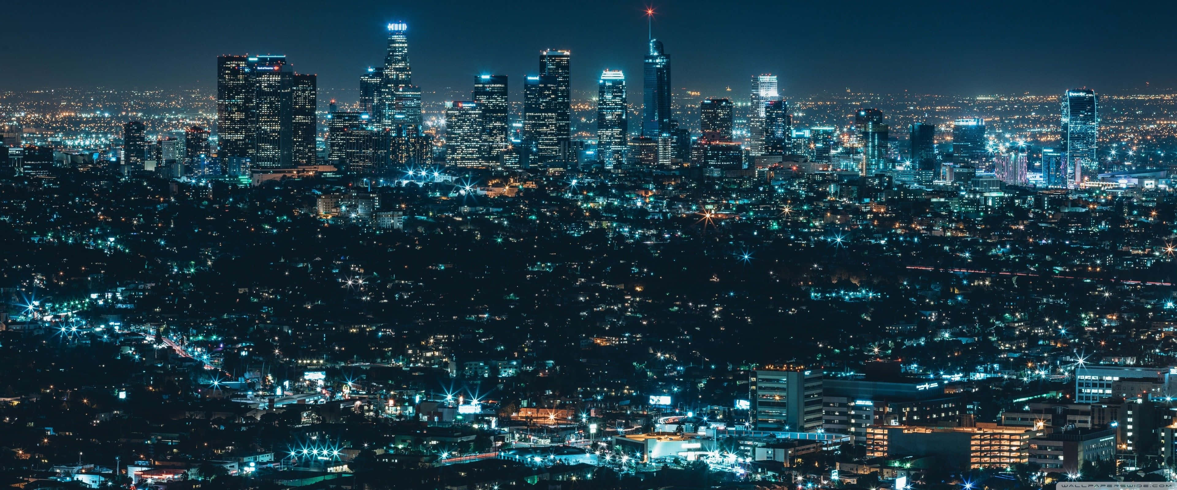 Apple 3840x1600 桌布 壁紙 — 廣闊的夜景城市景觀，高聳的摩天大樓在黑暗的天空中閃耀。