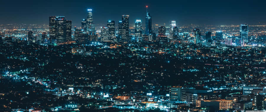 桌布 壁紙 — 廣闊的夜景城市景觀，高聳的摩天大樓在黑暗的天空下發光。