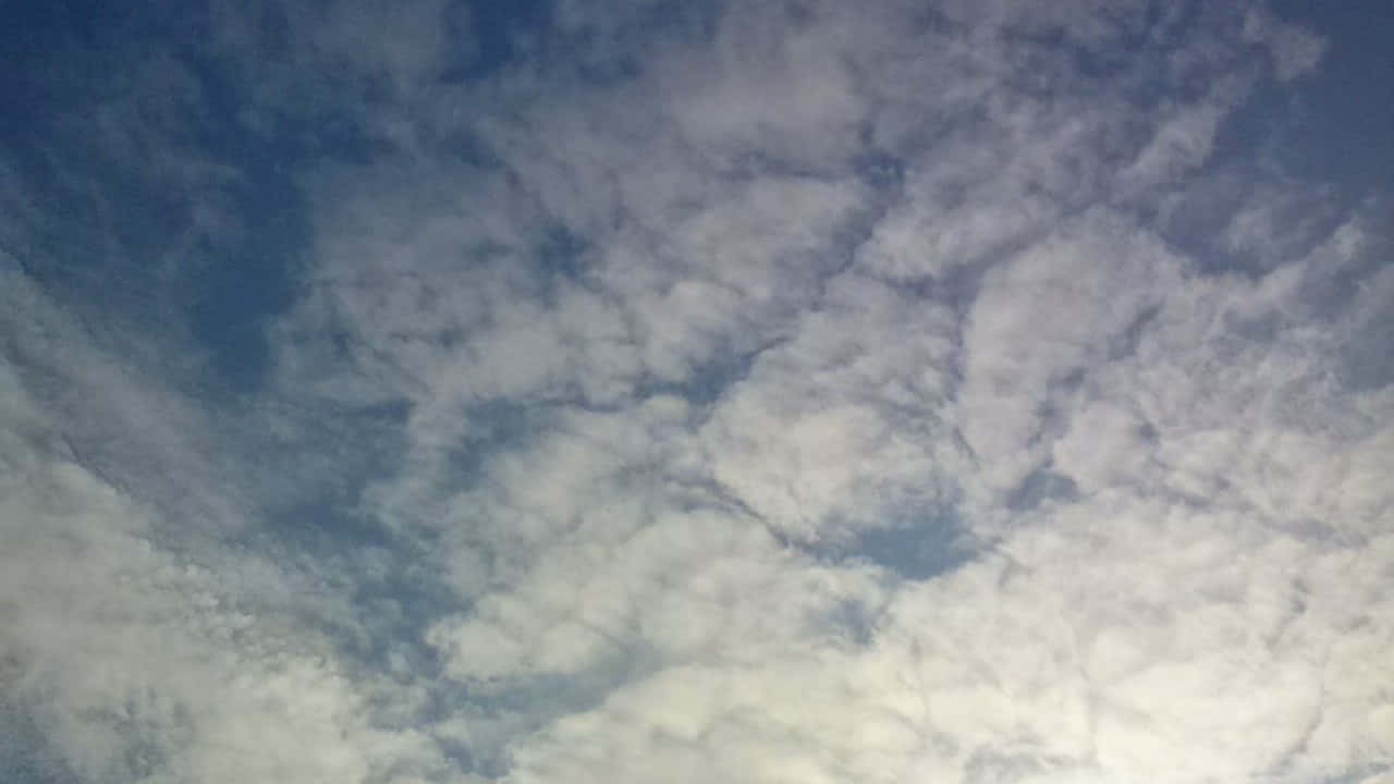 SKY-8 壁紙 — 廣闊的天空，充滿柔軟的白色和灰色雲朵，在深藍色的畫布上飄移。