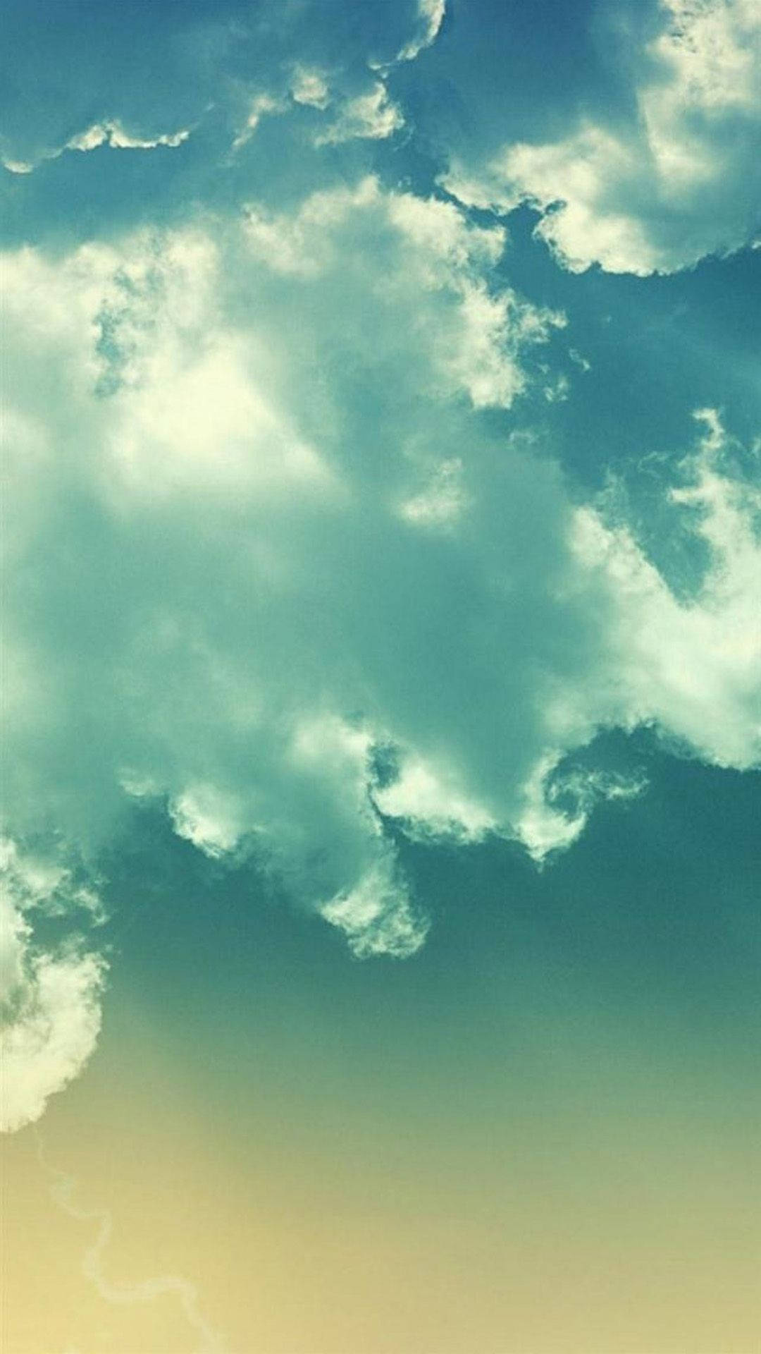 Bright iPhone 桌布 壁紙 — 廣闊的天空佈滿柔軟的棉花雲，在漸層的日落背景下散發出青綠色和奶油色的光芒。