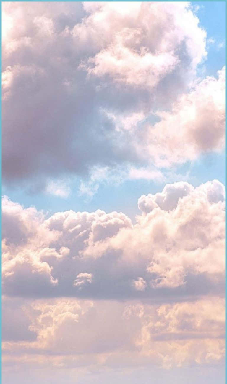 雲朵 桌布 壁紙 — 廣闊的天空充滿了柔和的粉彩雲朵，在溫暖的日落色調中閃耀，映襯著淡藍色的背景。