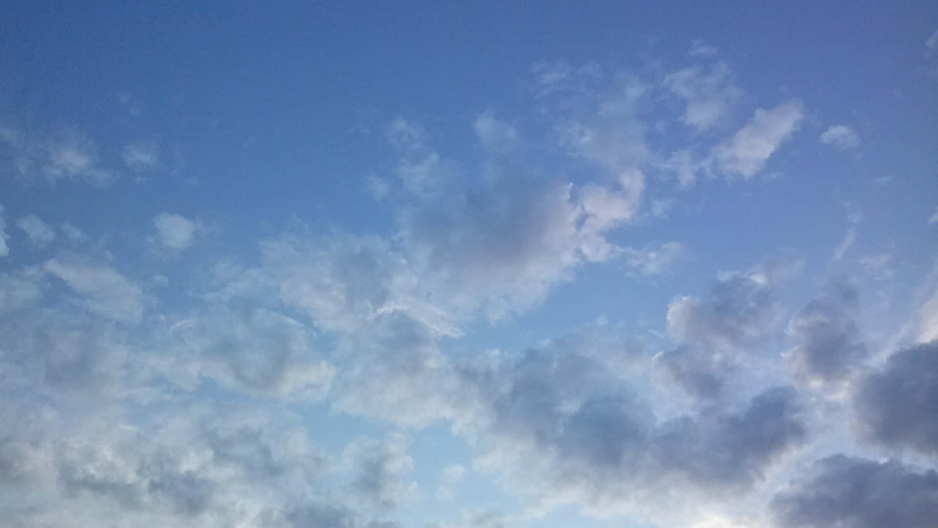 SKY-28 壁紙 — 廣闊的天空藍天點綴著柔軟的白色和灰色雲朵，懶洋洋地飄過地平線。