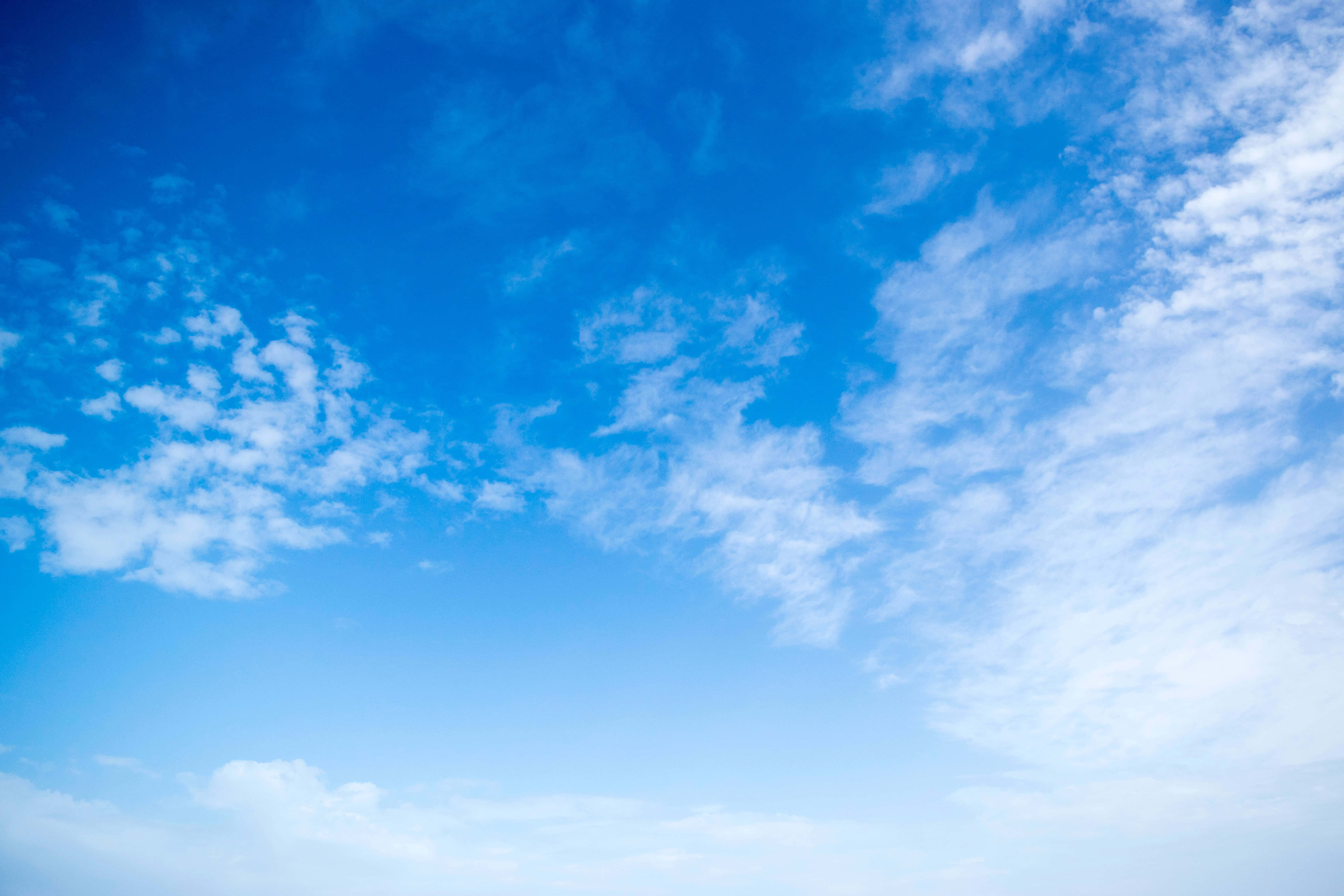 Blue Sky 桌布 壁紙 — 廣闊的天藍色天空，充滿了輕柔的白雲，緩緩飄過地平線。