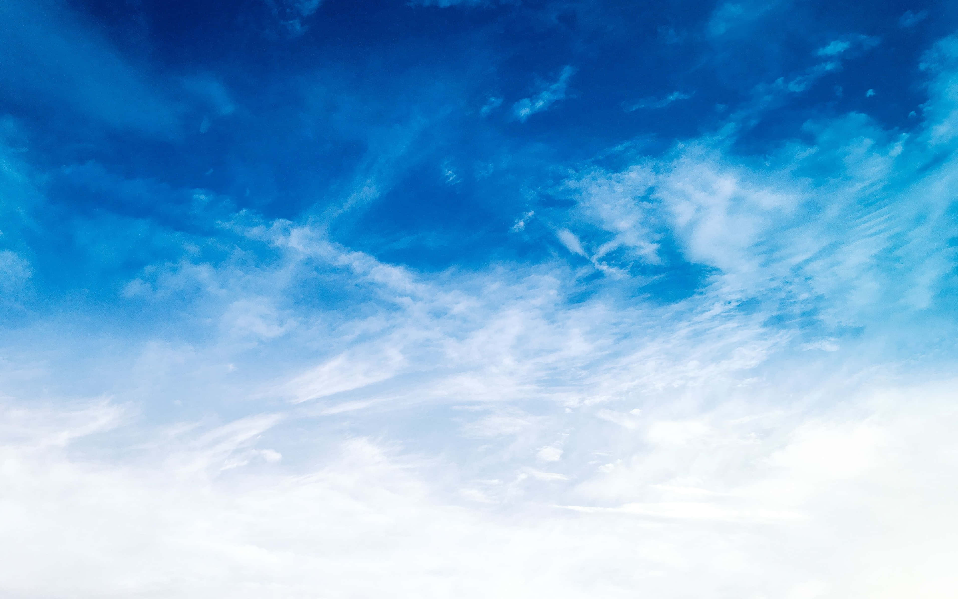 Clouds 4K 桌布 壁紙 — 廣闊的天藍色天空，充滿了輕柔的白雲，在明亮的藍色空間中飄移。