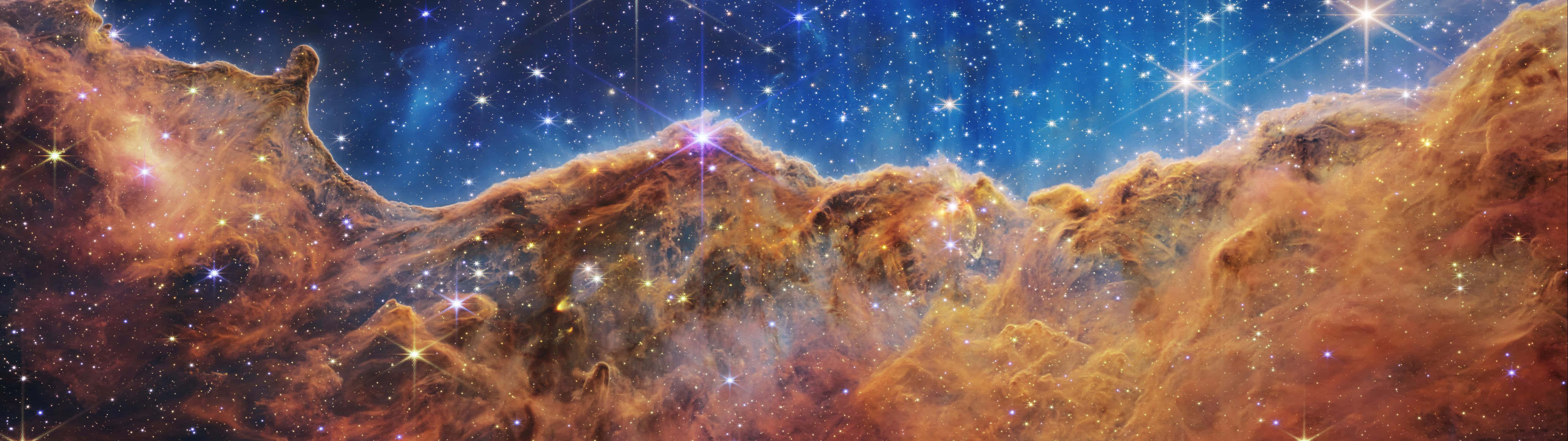 5120x1440 Dual Screen 桌布 壁紙 — 廣闊的宇宙星雲，帶有發光的橙色雲朵和閃爍的星星，襯托著深藍色的太空。