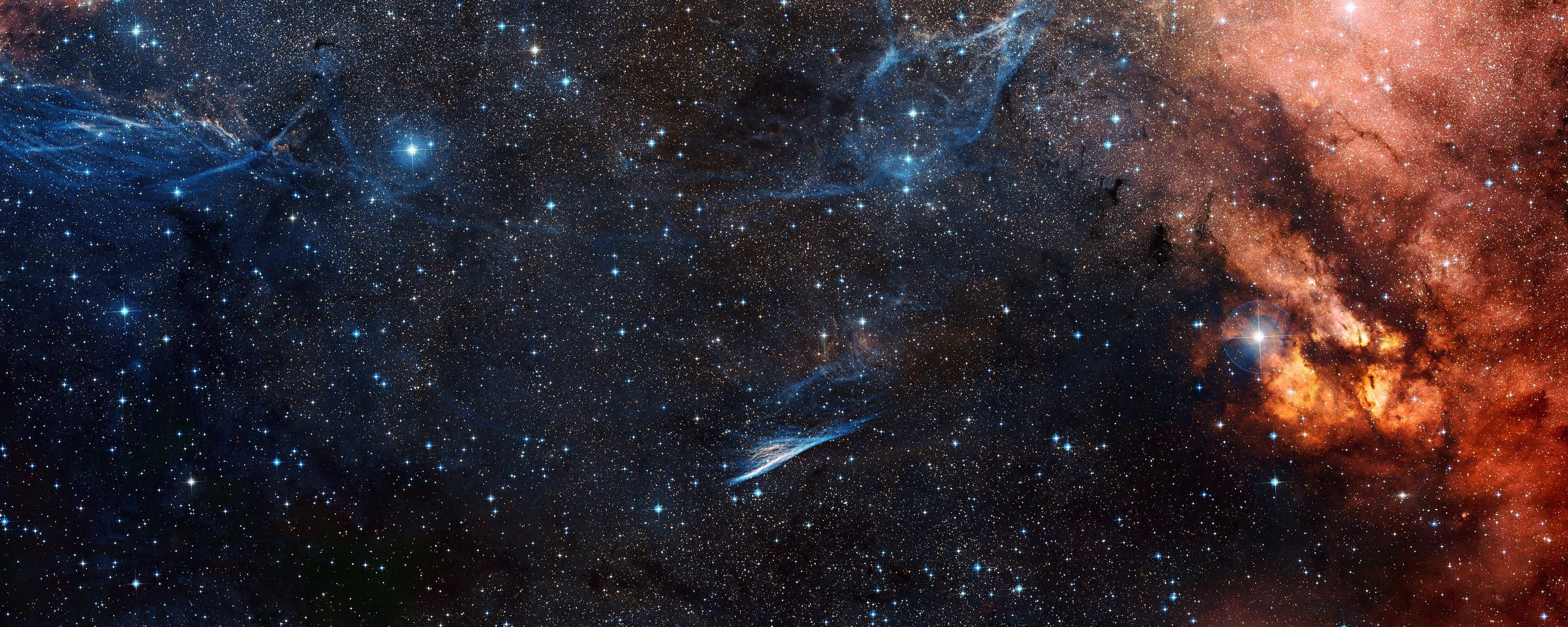 high 桌布 壁紙 — 廣闊的宇宙空間，充滿了在無數閃爍星星間旋轉的發光橙色和藍色星雲。