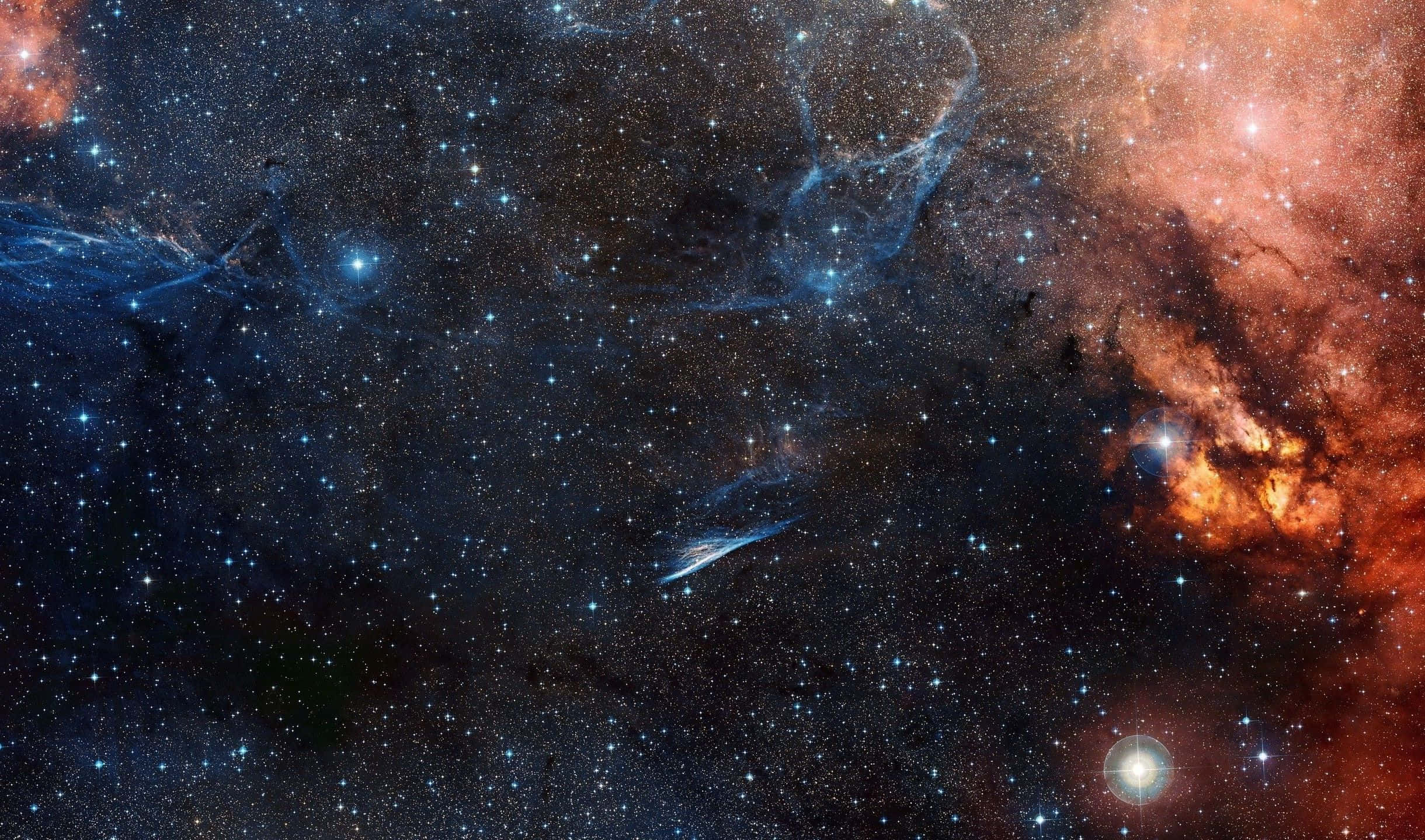2440x1440 桌布 壁紙 — 廣闊的宇宙空間，充滿了發光的星雲，在佈滿星辰的黑色虛空中旋轉，呈現熾熱的橙色和冷藍色。