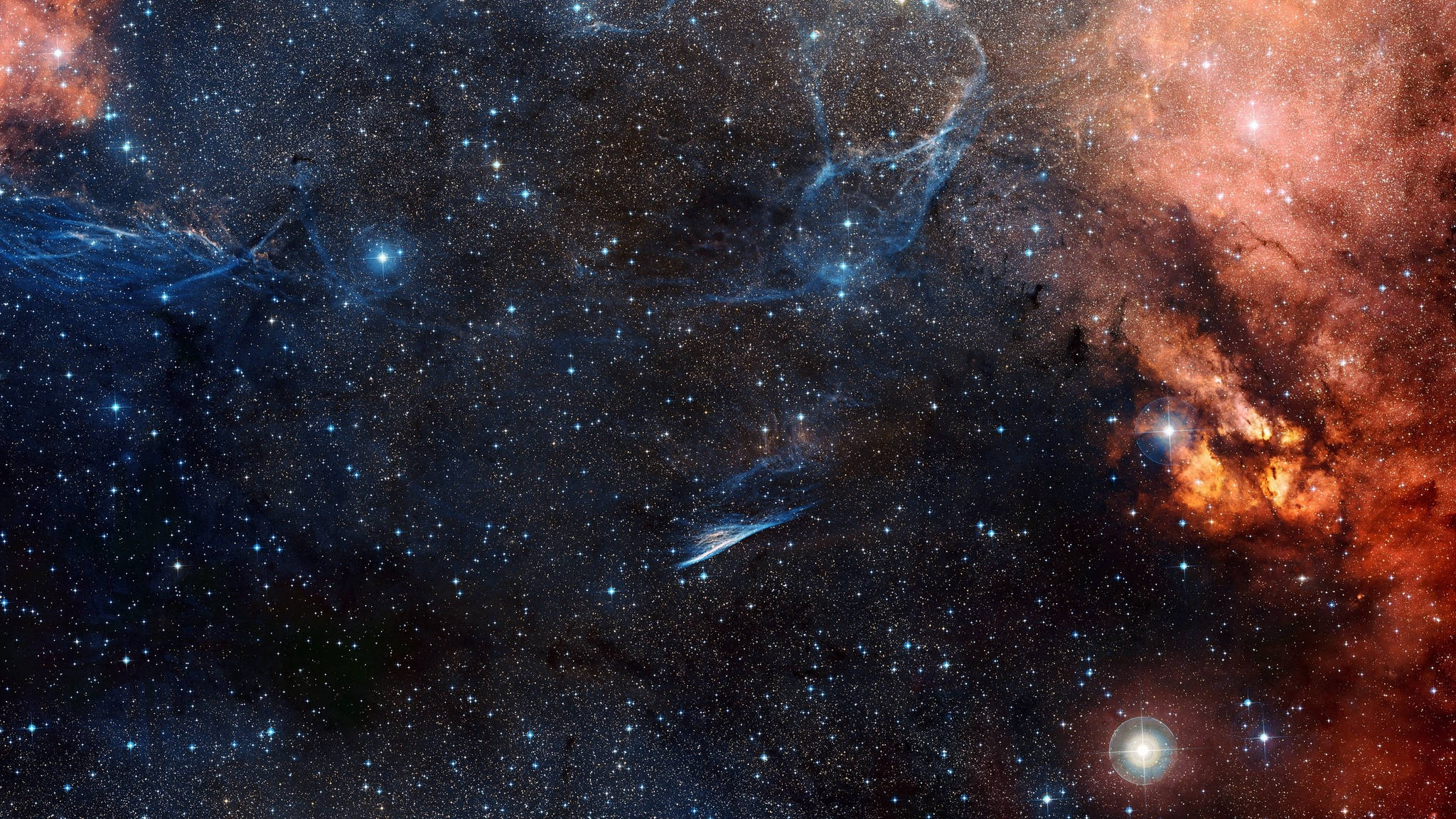 銀河 桌布 壁紙 — 廣闊的宇宙空間，充滿了發光的橙色和藍色星雲，在無數閃爍的星星中旋轉。