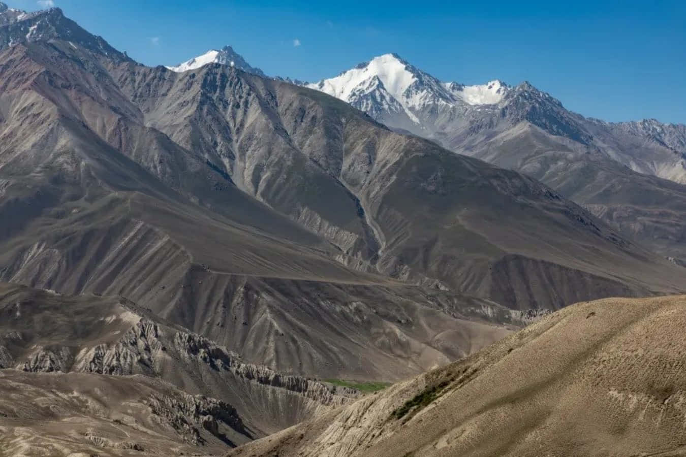 Afghanistan 桌布 壁紙 — 廣闊的山脈，白雪覆蓋的山峰和崎嶇的棕色山坡，在清澈的藍天下。