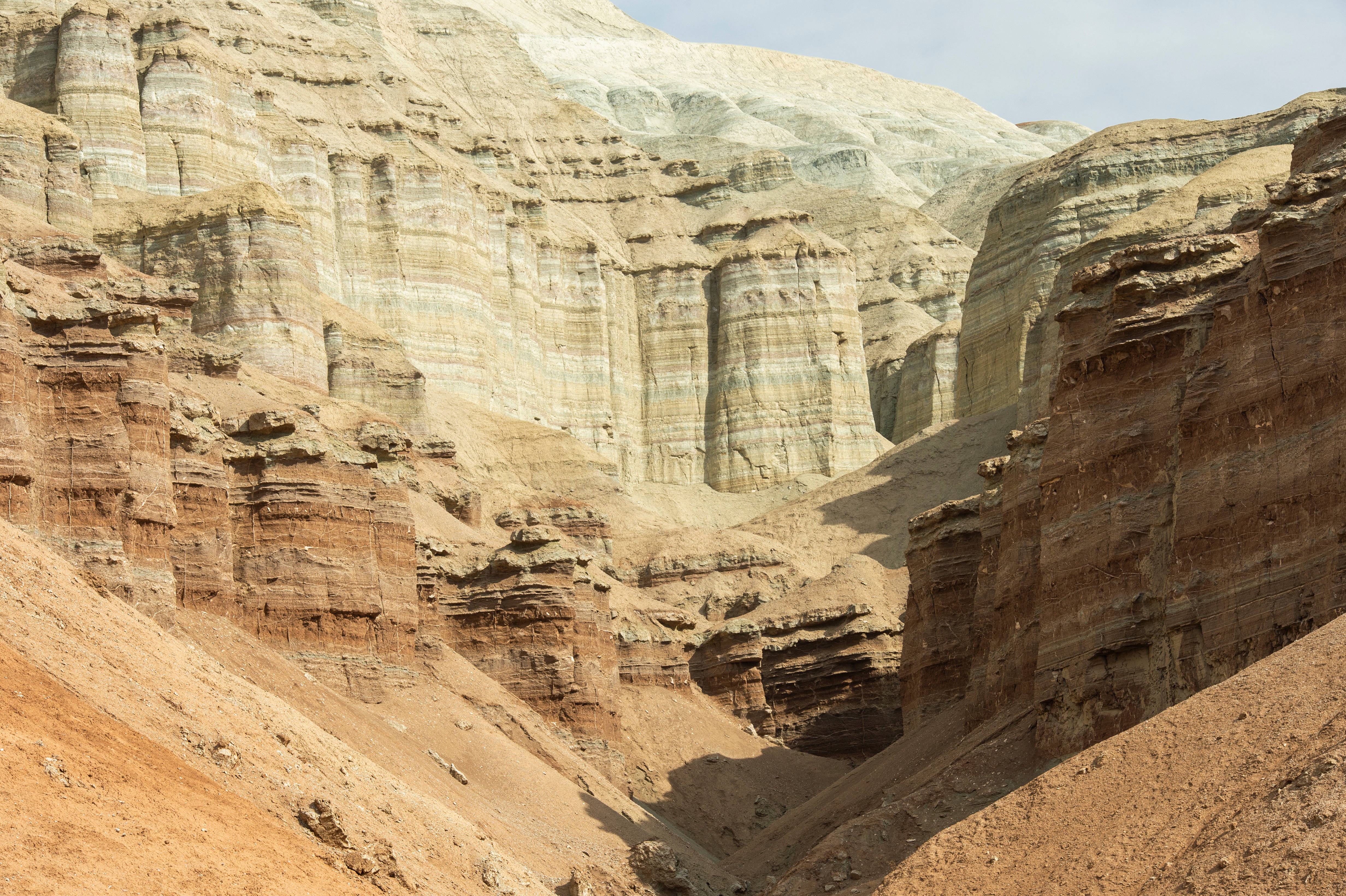Kazakhstan 桌布 壁紙 — 廣闊的峽谷，層層沉積岩呈現大地色調，天空蒼白。