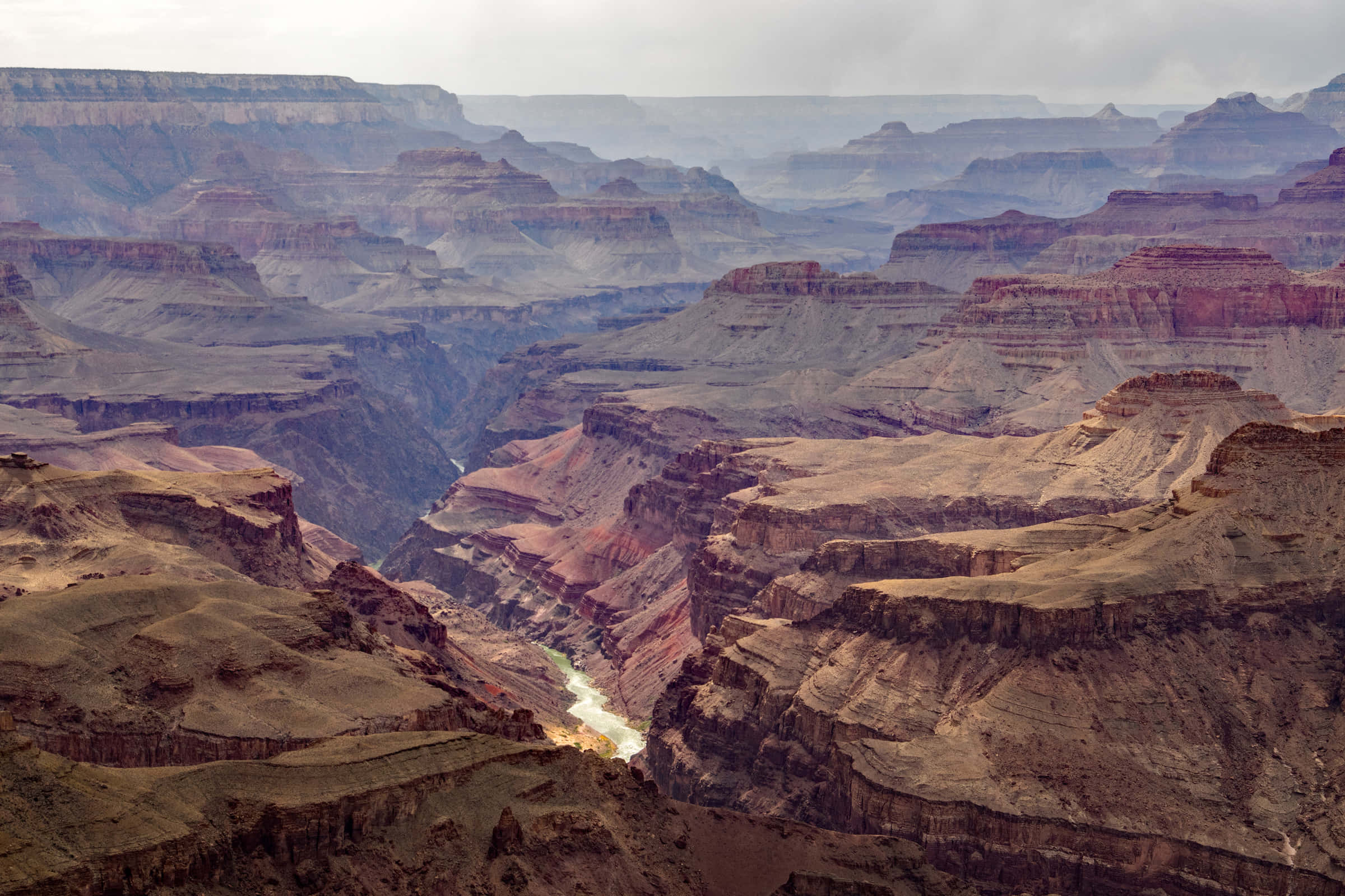 grand canyon 桌布 壁紙 — 廣闊的峽谷，層狀紅色岩層，下方有蜿蜒河流，天空多雲。