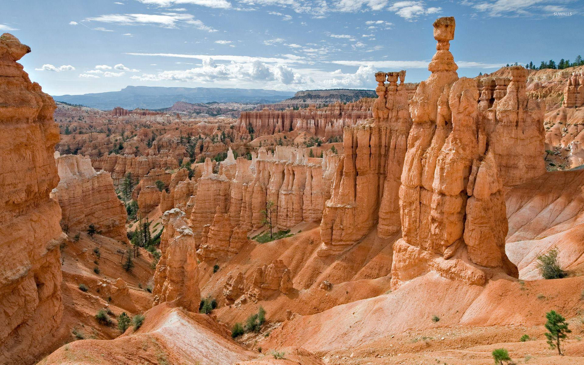 Rock 桌布 壁紙 — 廣闊的峽谷景觀，高聳的橙色 Hoodoos 岩石，在明亮的藍天下有零星雲朵。