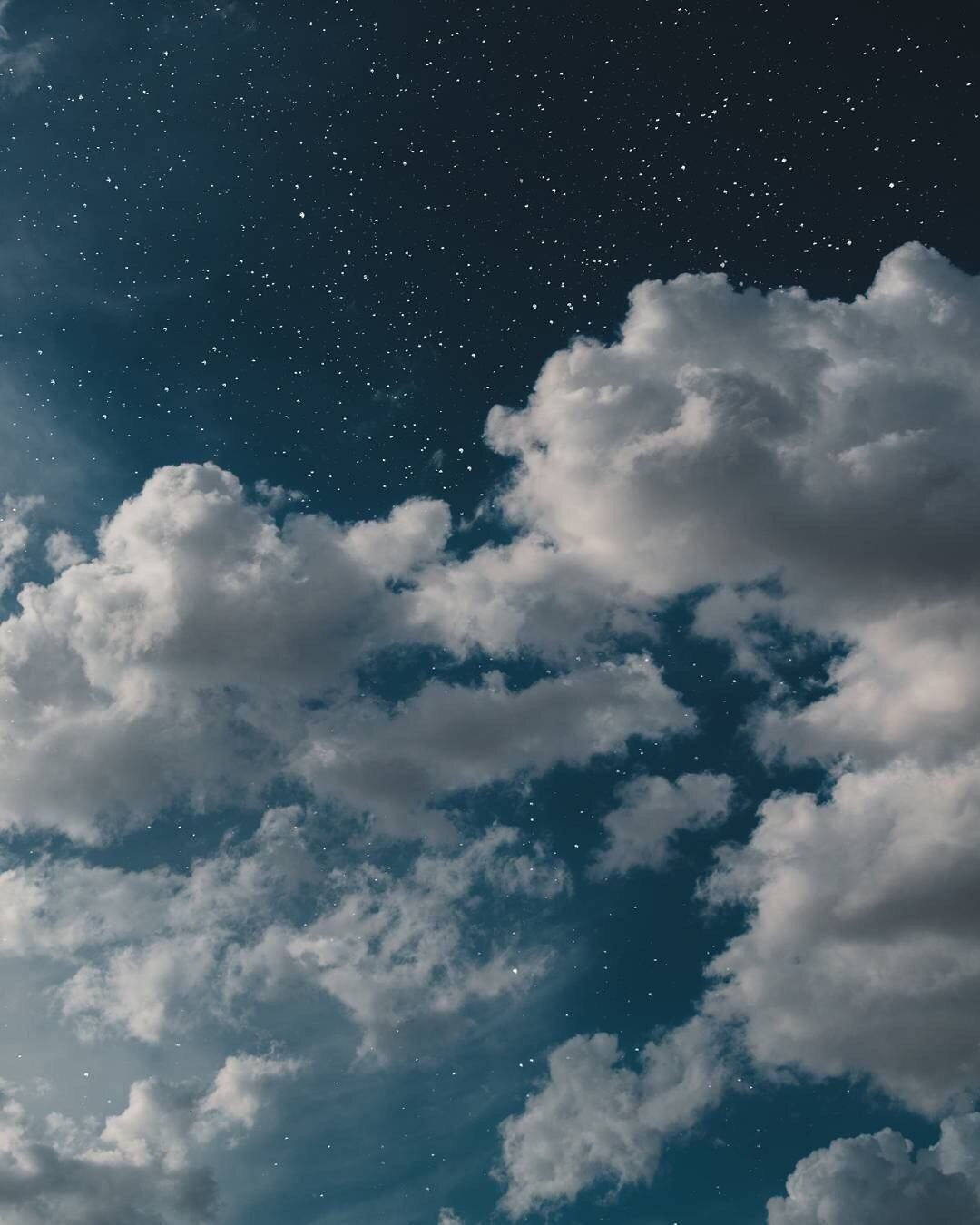 藍色美學手機 桌布 壁紙 — 廣闊的星空夜空，有豐盈的白雲在深靛藍色的天空中飄移。
