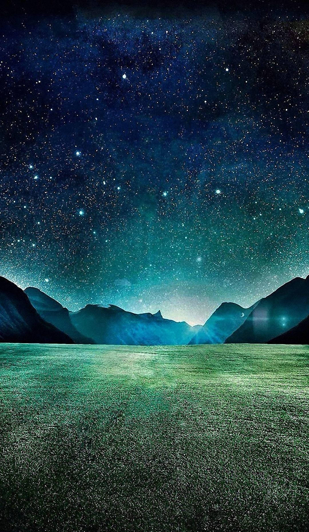 HD nature phone 桌布 壁紙 — 廣闊的星空夜空在一個寧靜的山谷上方發光，山谷中有輪廓分明的山脈和發光的綠色草地。