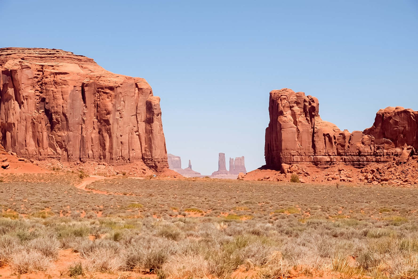 Arizona 桌布 壁紙 — 廣闊的沙漠景觀，在清澈的藍天下聳立著高聳的紅色砂岩層。