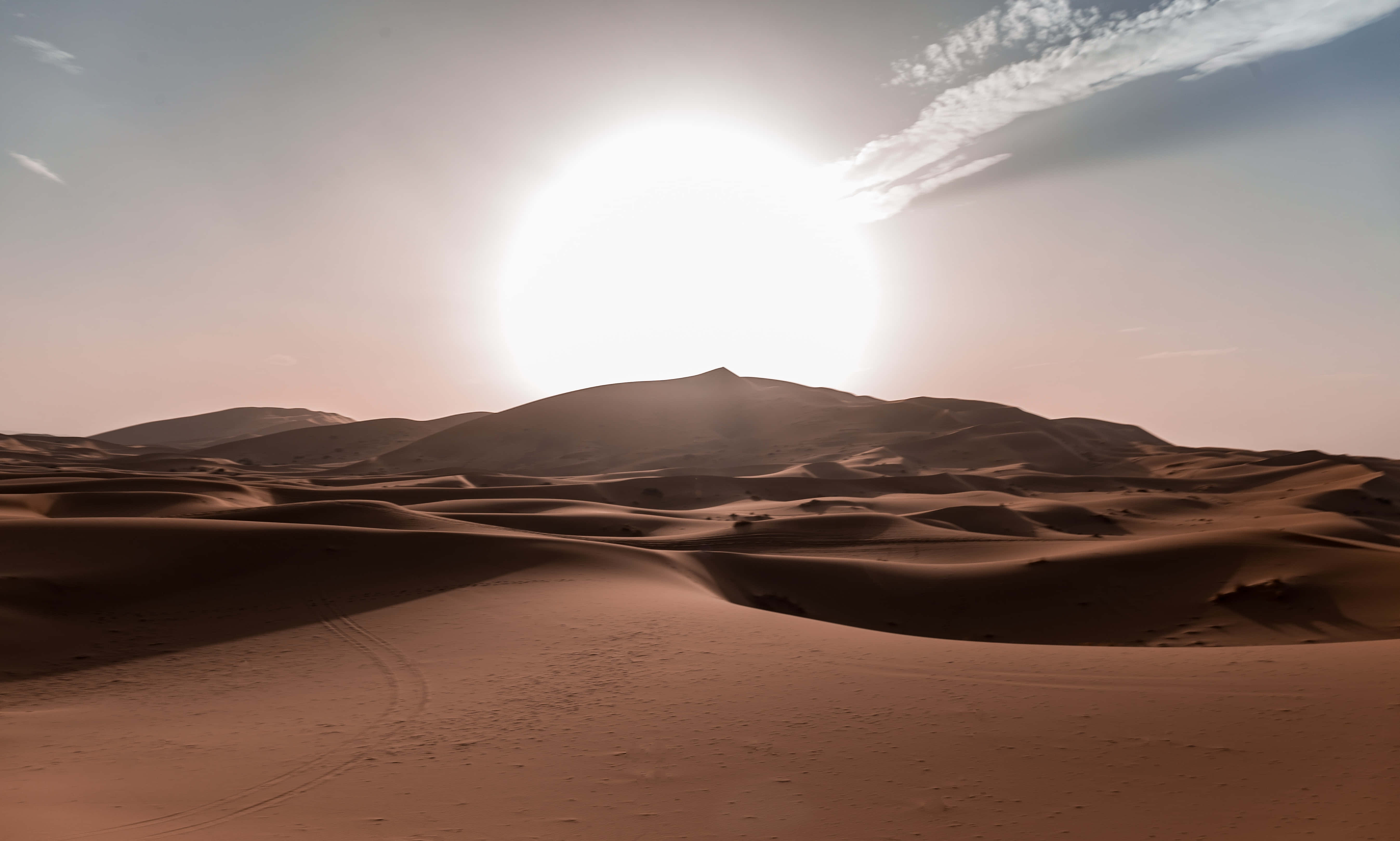 Sand Dunes 桌布 壁紙 — 廣闊的沙漠景觀，日落時分，起伏的沙丘和明亮的太陽投下長長的陰影。