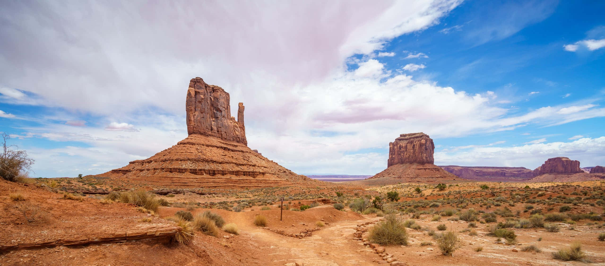 Arizona 桌布 壁紙 — 廣闊的沙漠景觀，高聳的紅色岩層，明亮的藍天，散佈著雲朵。
