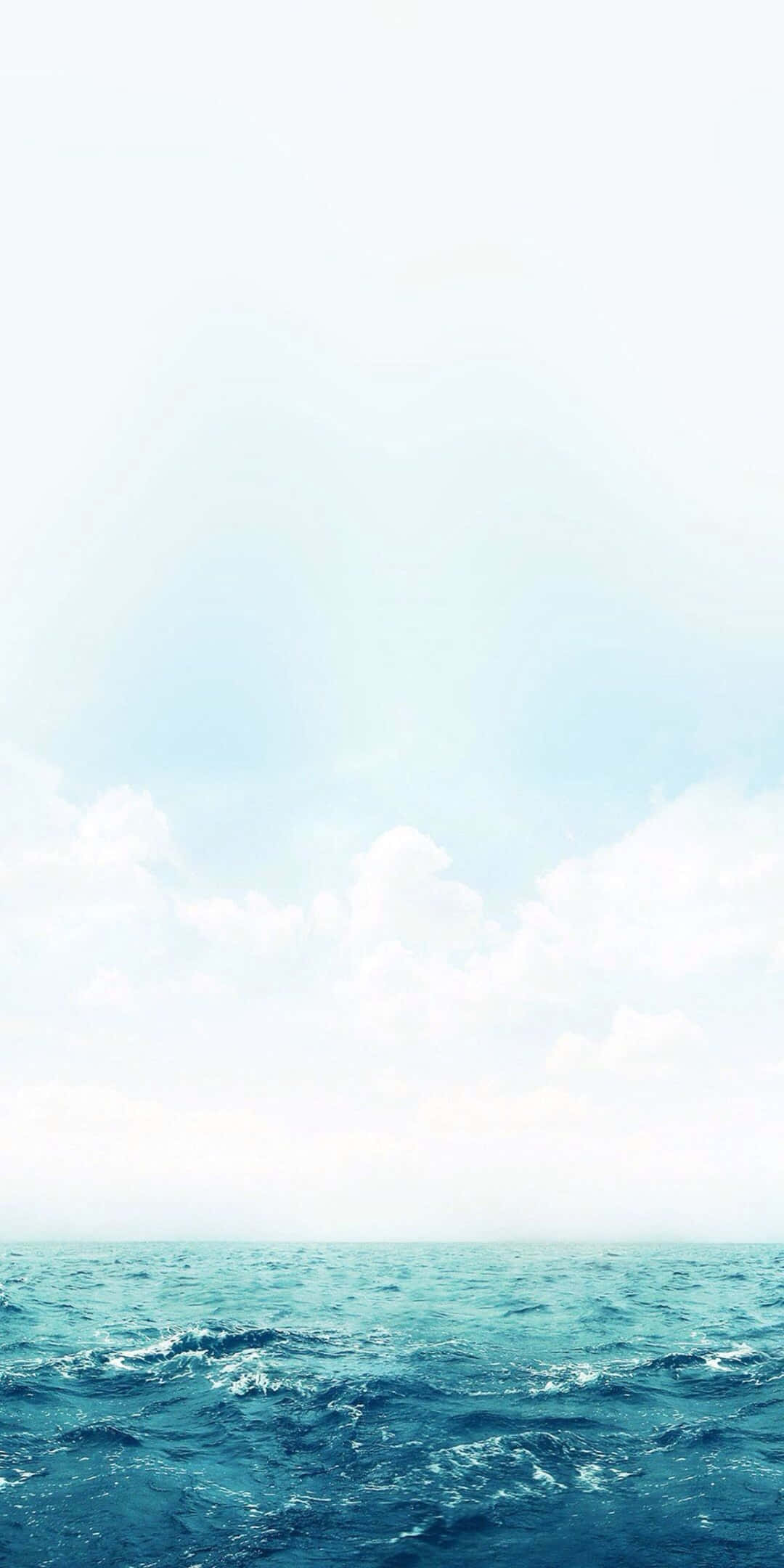 Pixel 3 Beach 桌布 壁紙 — 廣闊的海洋波浪在柔和的藍天下，散佈著白雲和溫和的陽光中蕩漾。