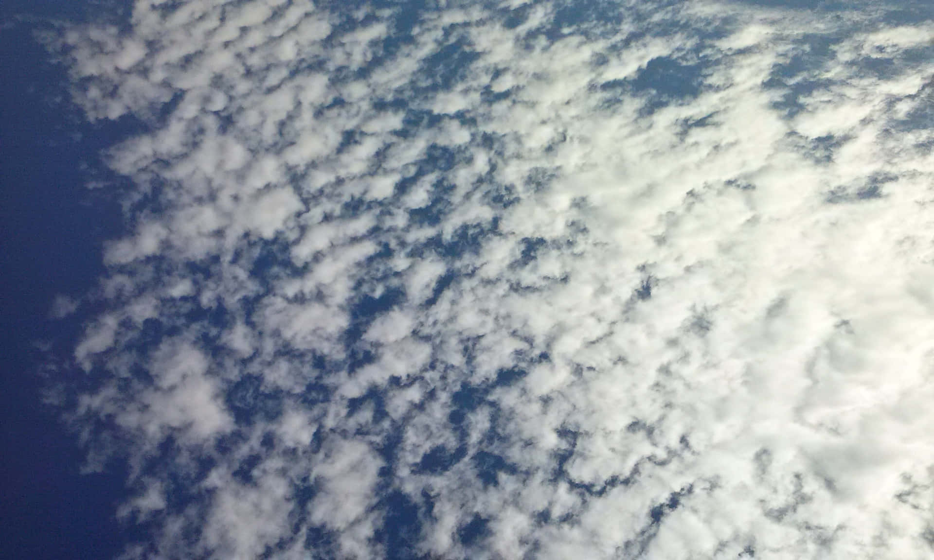 SKY-14 壁紙 — 廣闊的深藍色天空，充滿柔軟的白色積雲飄過畫面。