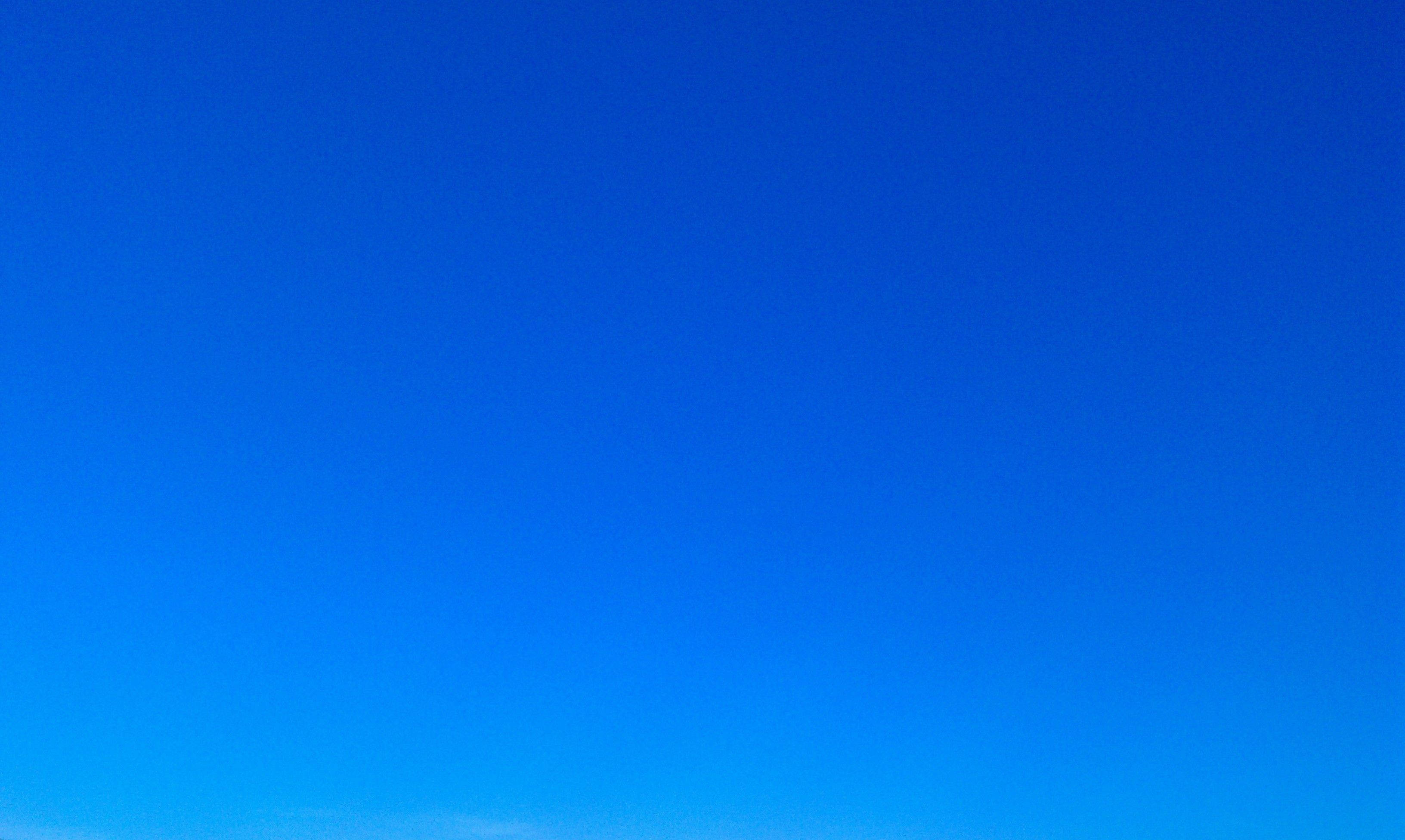 Blue Sky 桌布 壁紙 — 廣闊的漸變藍天，從深皇家藍過渡到明亮的蔚藍色，地平線附近有淡淡的縷縷雲彩。