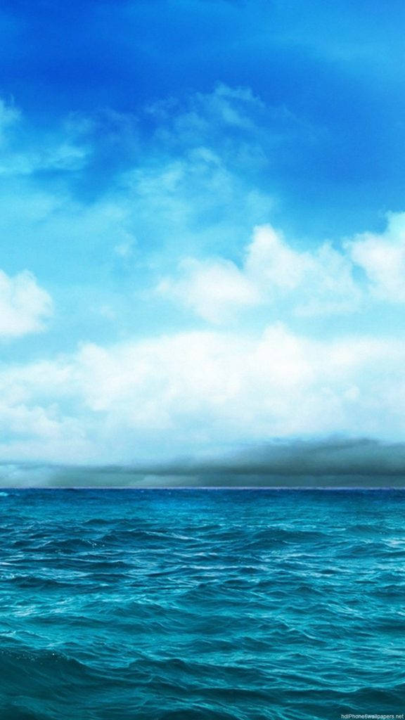 Blue iPhone 桌布 壁紙 — 廣闊的綠松色海浪與明亮的藍天相遇，天空中有蓬鬆的白雲和遙遠的黑暗地平線。