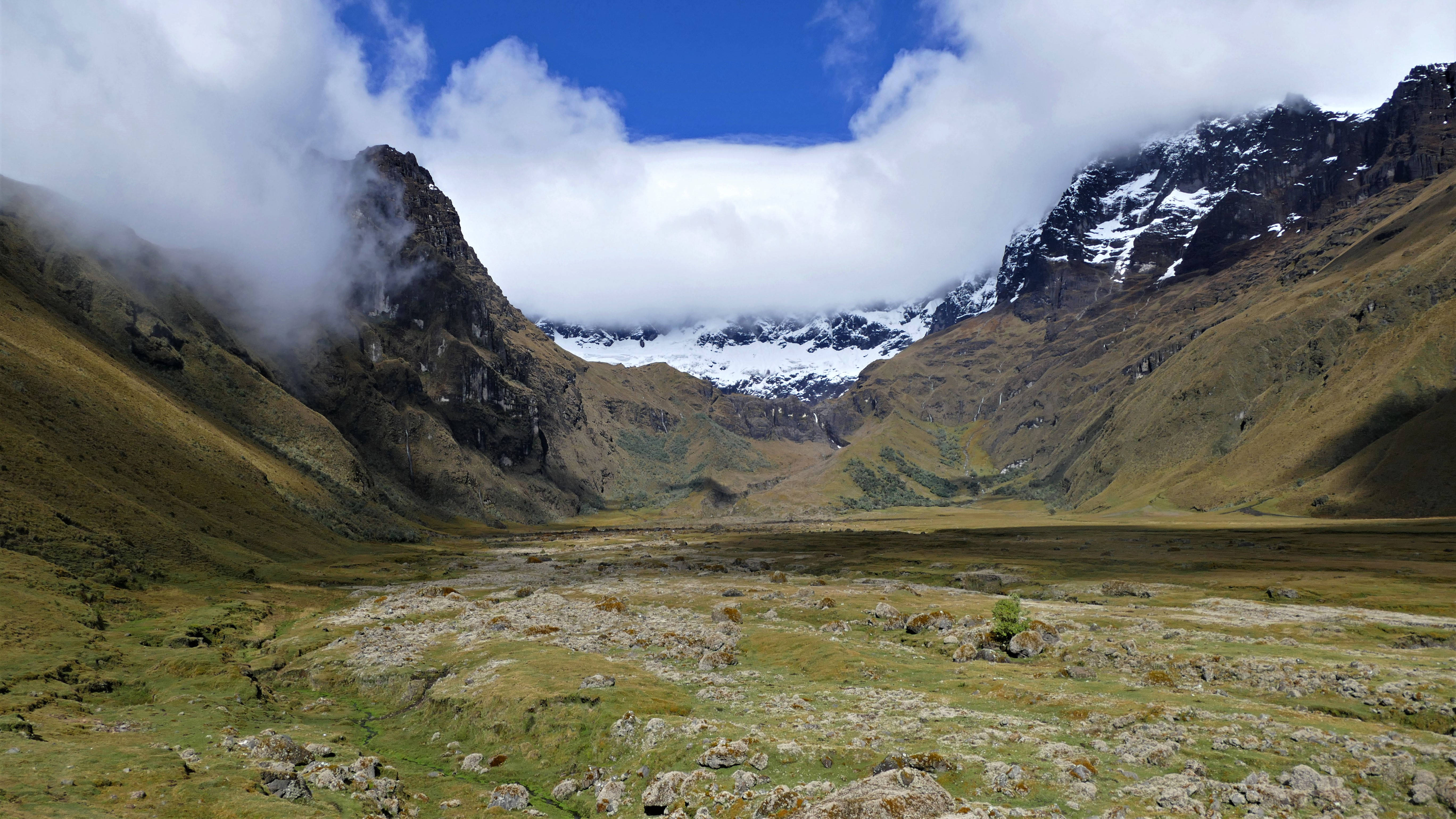 Ecuador 桌布 壁紙 — 廣闊的綠色山谷，坐落於崎嶇的山脈之間，山頂積雪，雲霧在高地間飄移。