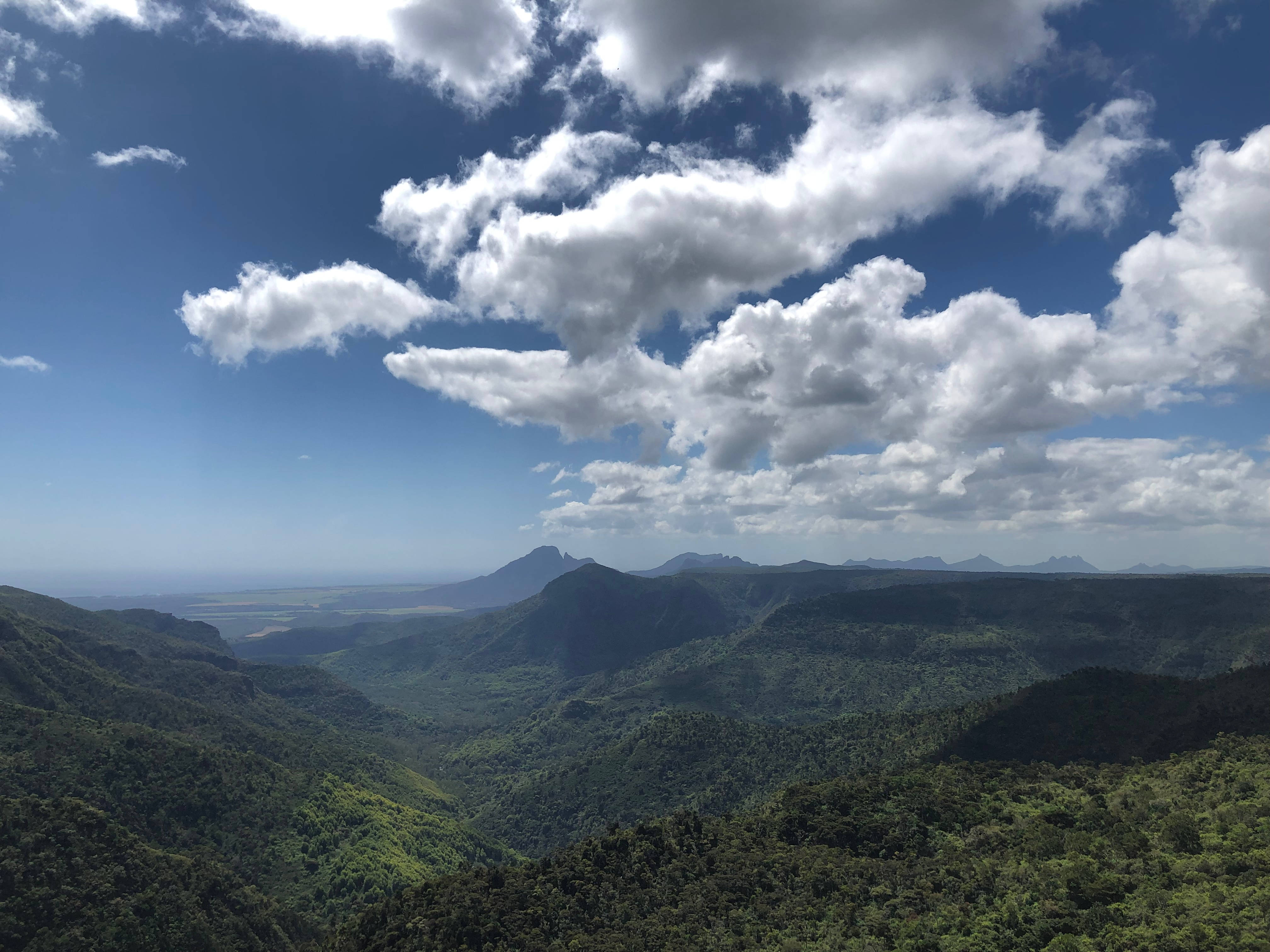 Mauritius 桌布 壁紙 — 廣闊的綠色山谷在點綴著蓬鬆白雲的明亮藍天下延伸。
