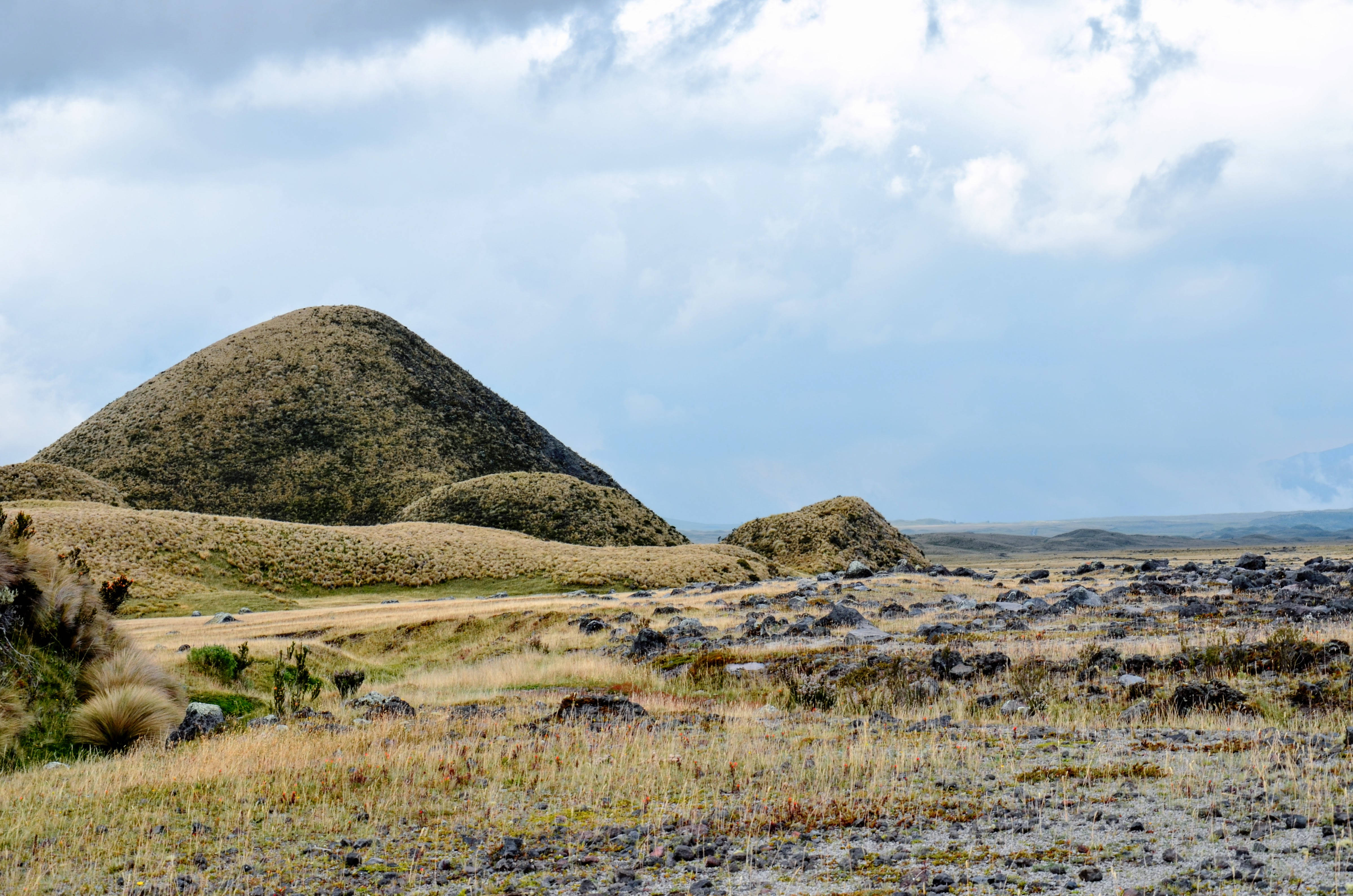 Ecuador 桌布 壁紙 — 廣闊的草原上點綴著火山錐，天空部分多雲。