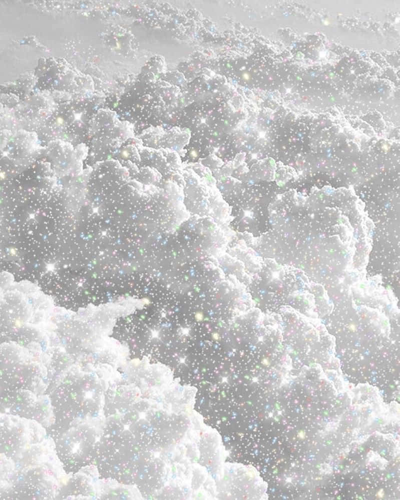 白色美學動圖 桌布 壁紙 — 廣闊的蓬鬆雲朵在柔和的灰色天空中閃爍著彩虹色的亮粉，營造出神奇空靈的氛圍。
