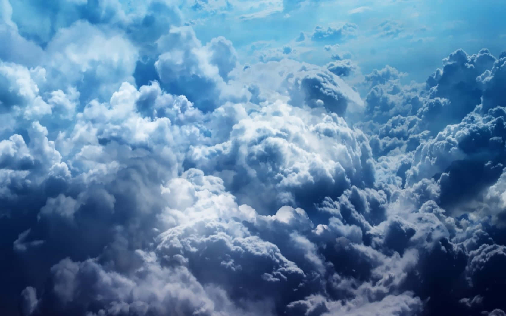 Cloud 桌布 壁紙 — 廣闊的蓬鬆雲朵在藍色和白色的色調中延伸，穿過明亮的天空，柔和的陽光透過雲層。