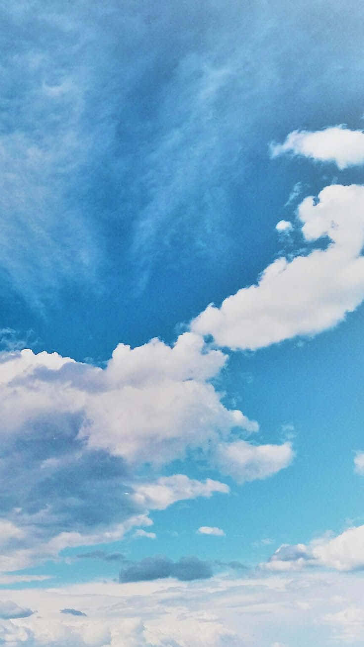 iPhone 桌布 壁紙 — 廣闊的藍天，充滿蓬鬆的白雲，在明亮的地平線上飄移。
