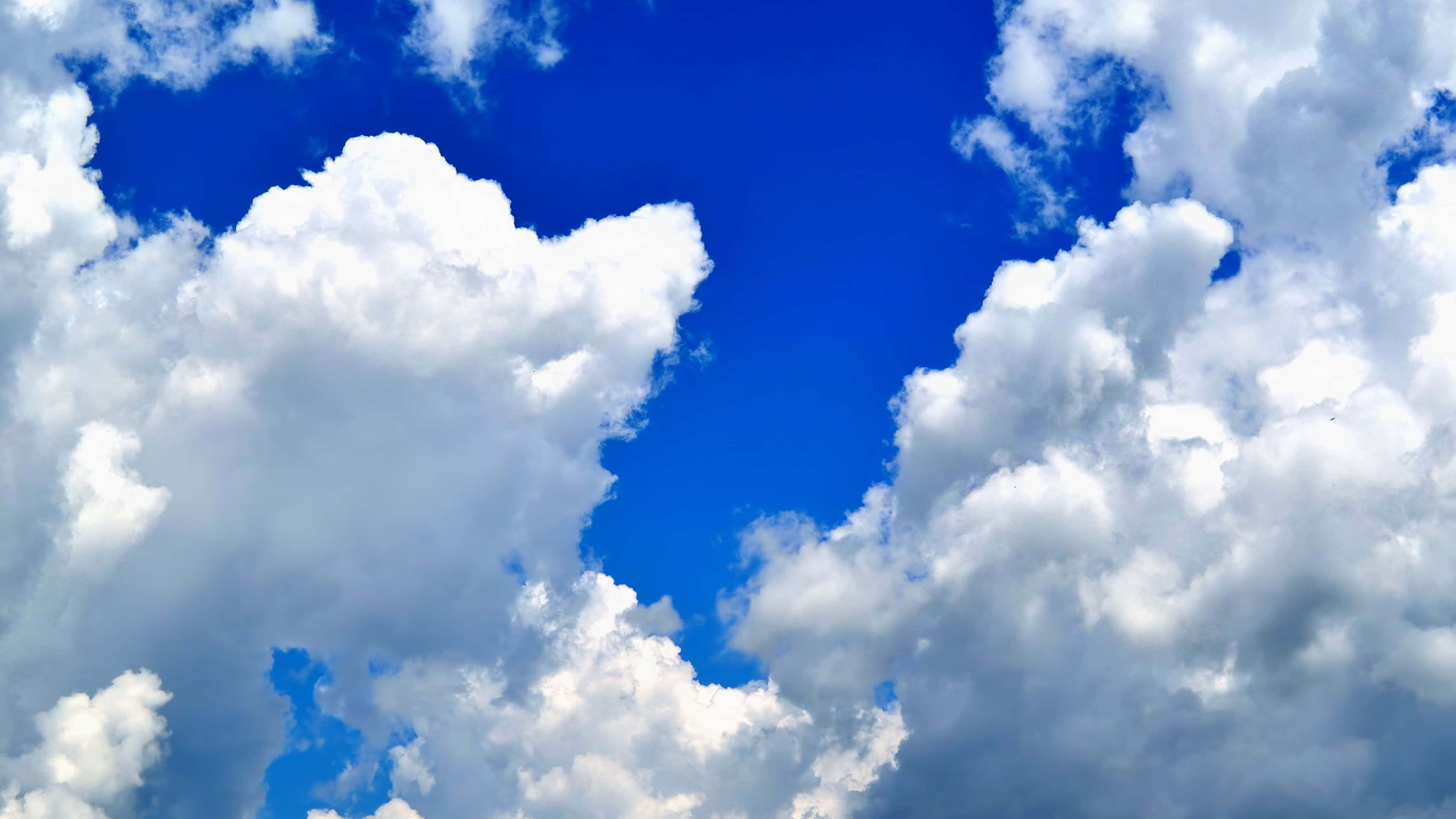 Clouds Aesthetics 桌布 壁紙 — 廣闊的藍天佈滿蓬鬆的白雲，在鮮豔的蔚藍背景下投下柔和的陰影。