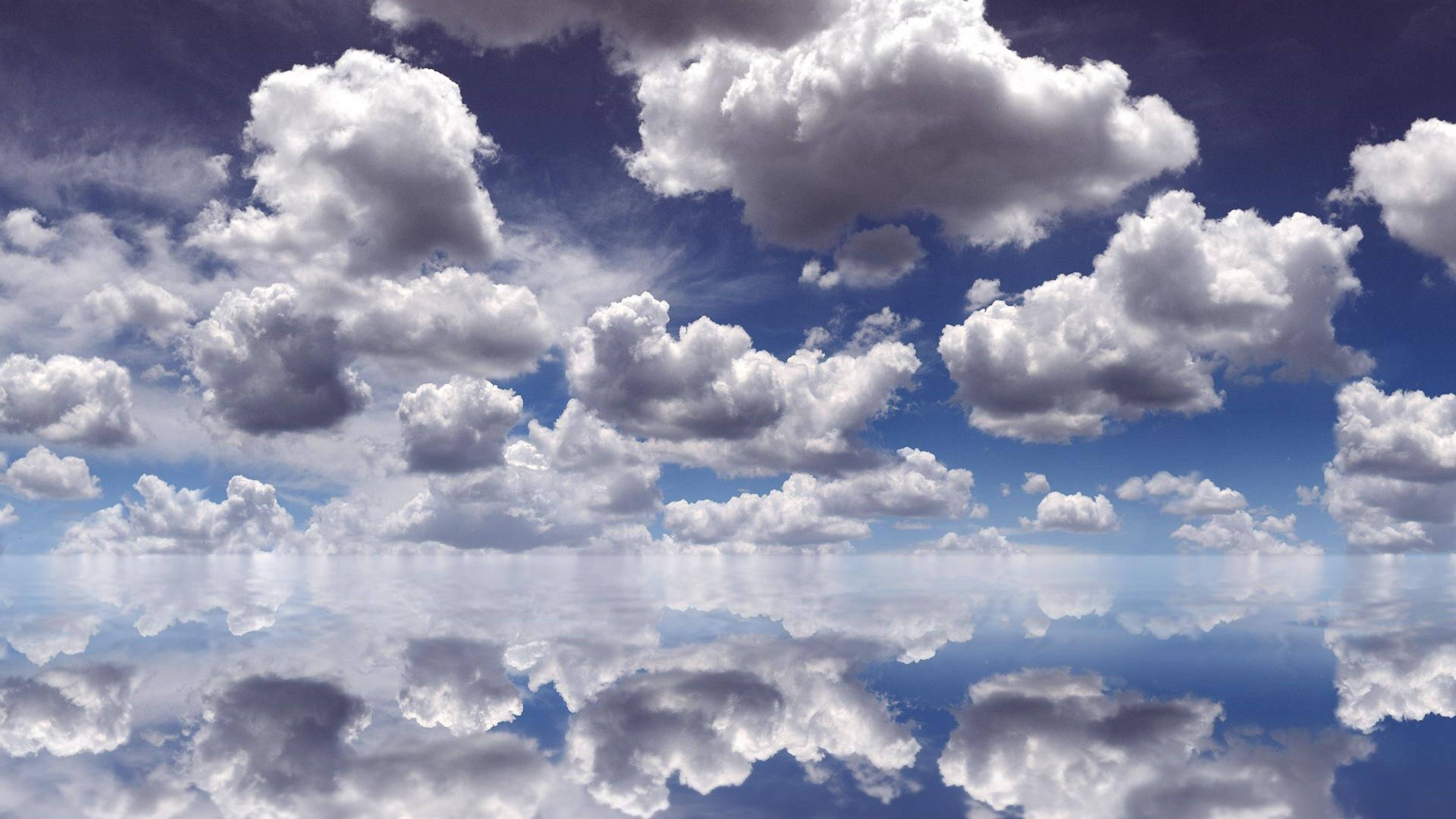 Clouds Aesthetics 桌布 壁紙 — 廣闊的藍天佈滿蓬鬆的白雲，完美地倒映在平靜如鏡的水面上。