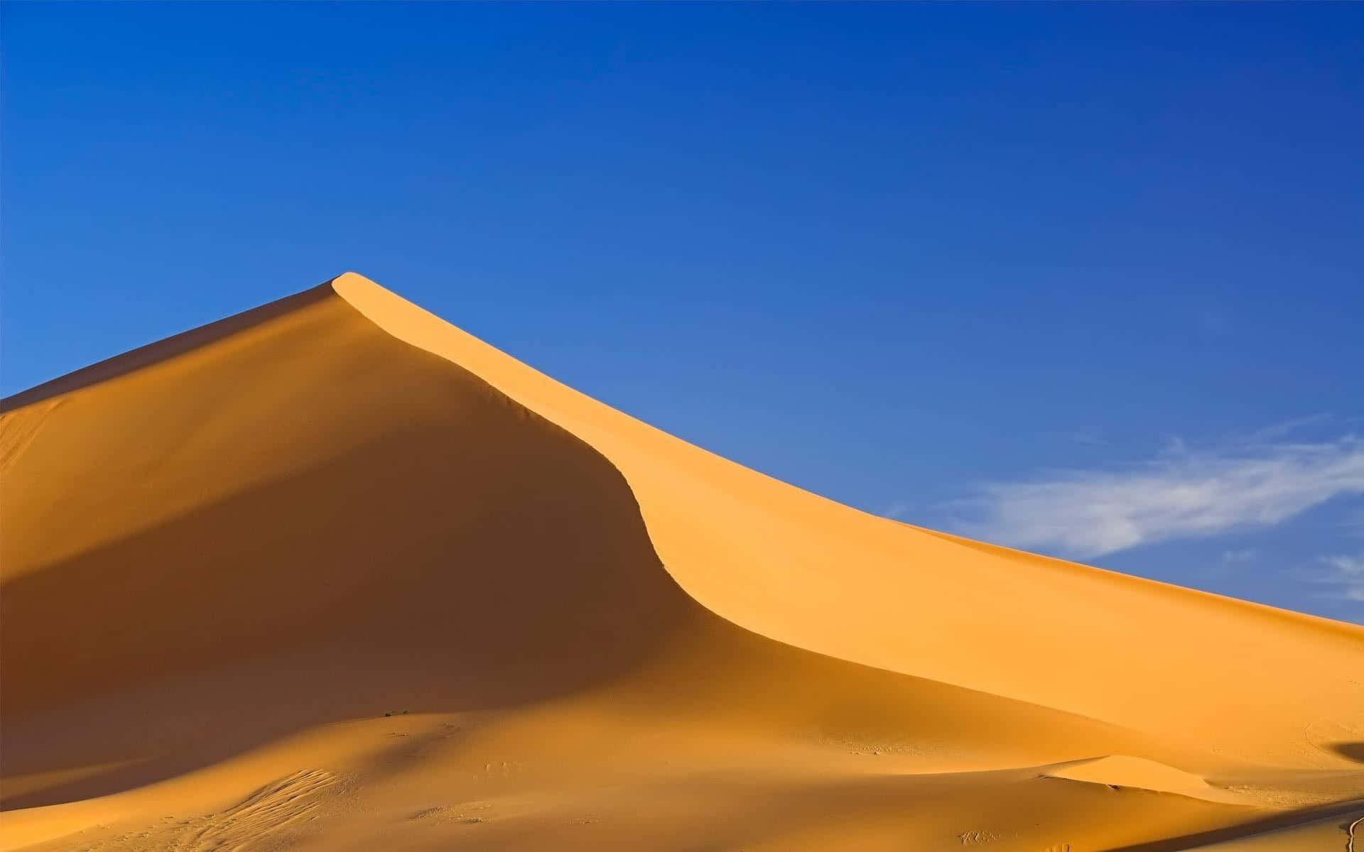 Sand Dunes 桌布 壁紙 — 廣闊的金色沙丘在清澈的藍天下彎曲，柔軟的白雲飄過。