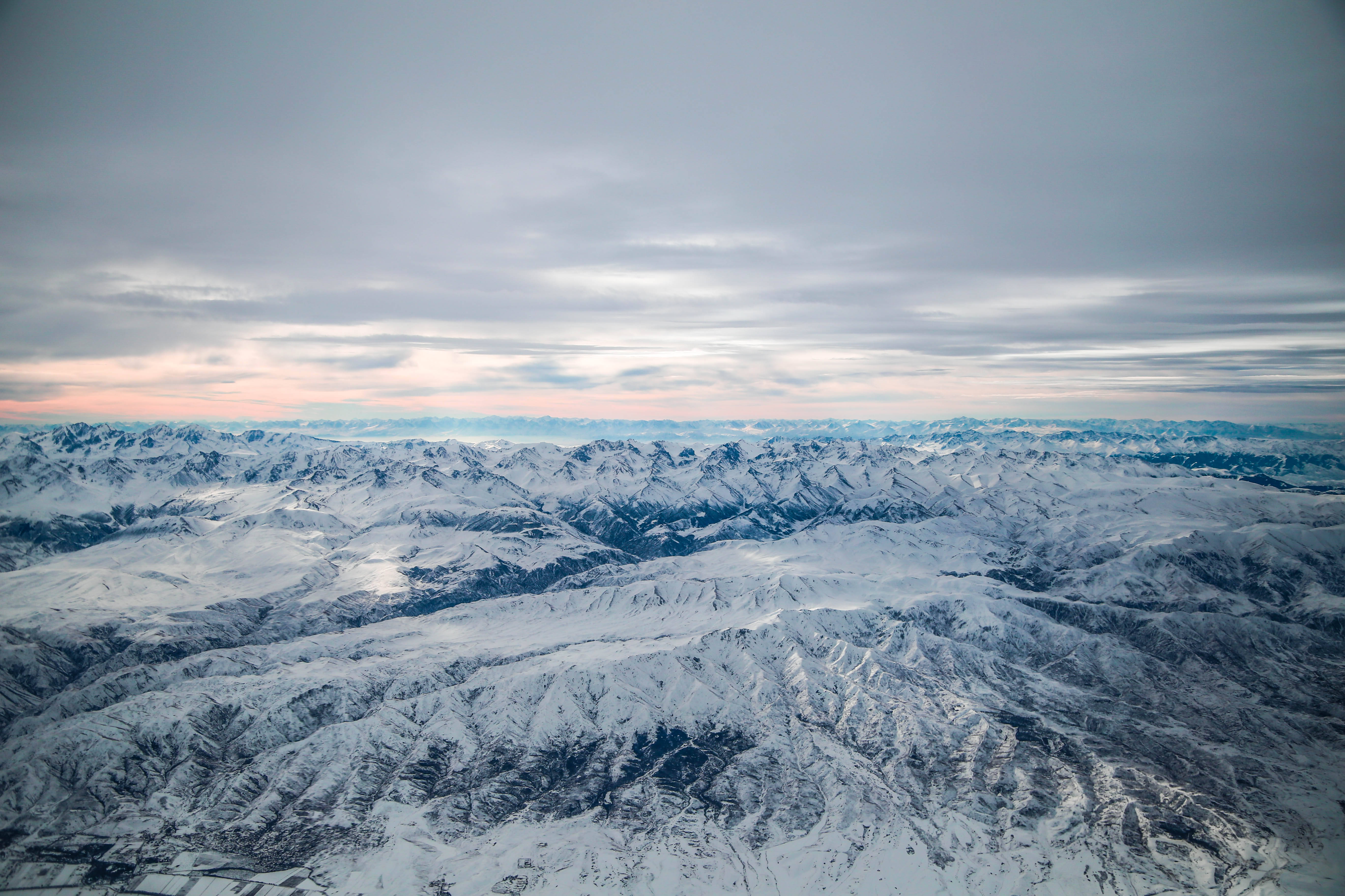 Tajikistan 桌布 壁紙 — 廣闊的雪山山脈在黎明時分柔和的粉彩天空下延伸。