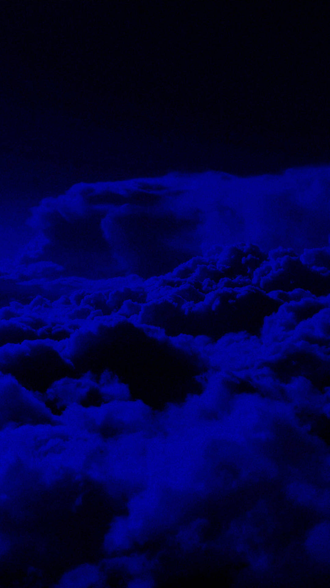  壁紙 — 廣闊的雲層在漆黑的天空中閃耀著深電藍色，營造出超現實的夜間氛圍。