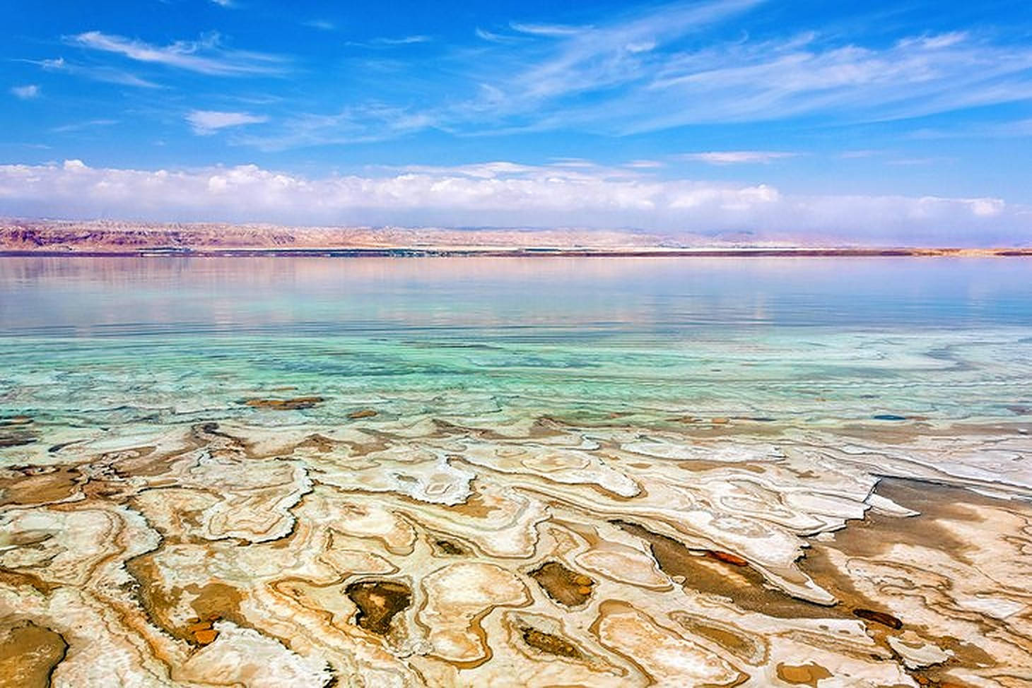 Jordan 桌布 壁紙 — 廣闊的鹽結晶海岸線在明亮藍天和縷縷白雲下與碧綠海水相接。