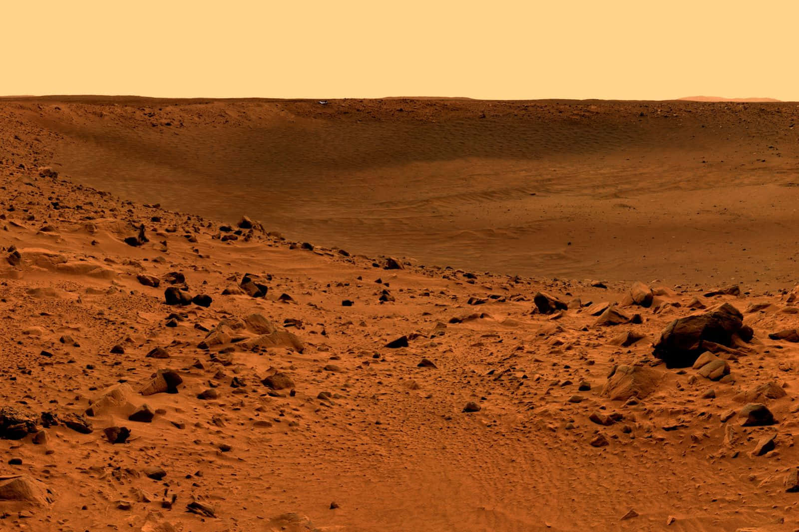 Mars Surface 桌布 壁紙 — 廣闊荒涼的火星景觀，鏽色沙丘和散落的岩石，籠罩在朦朧的橙色天空下。