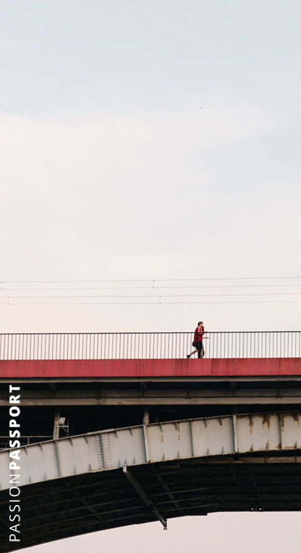 Minimalist Photography 桌布 壁紙 — 廣闊蒼白的天空下，一名身穿紅色衣服的孤獨跑者，大步跨過一座風化的鋼橋。