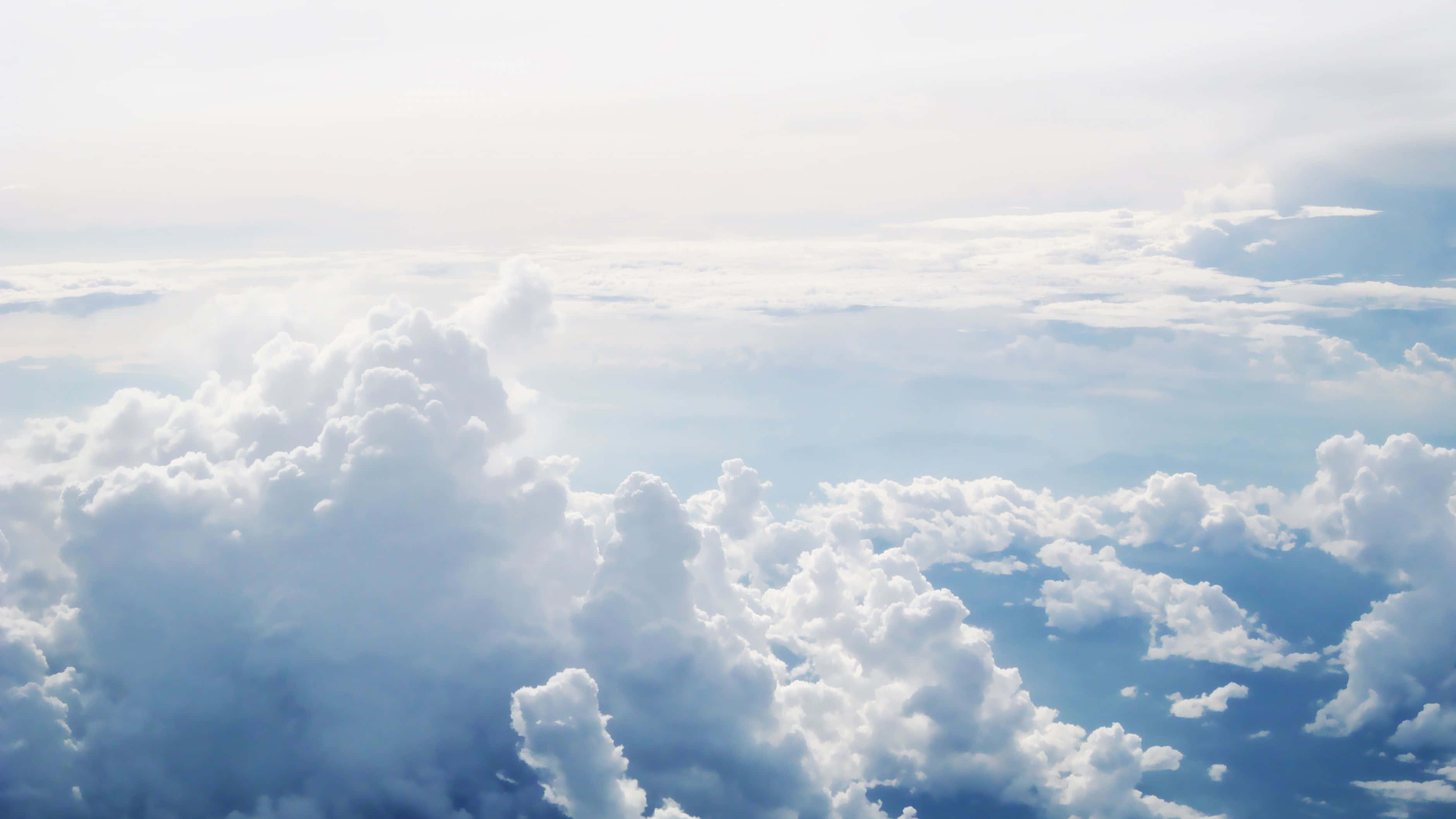 Clouds Aesthetics 桌布 壁紙 — 廣闊蓬鬆的白雲在深藍色的天空中飄動，從高空看到柔和陽光穿透。