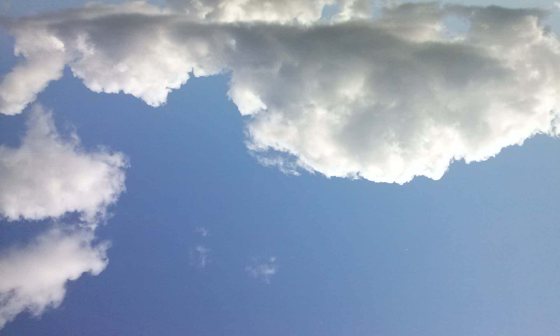 SKY-19 壁紙 — 廣闊藍天，一大片蓬鬆白雲佔據上方框架，下方散落著較小的雲絲。